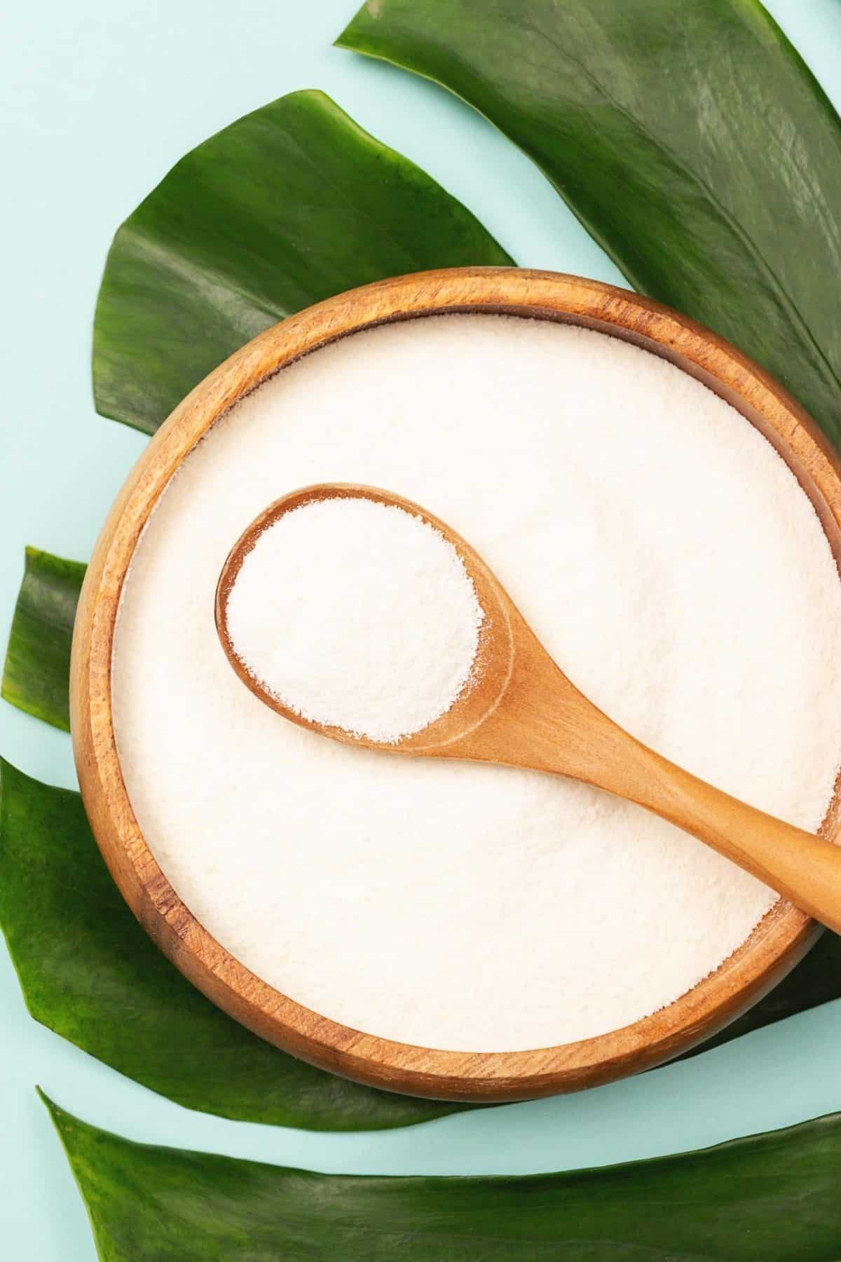 bowl of powdered collagen protein on top of a palm leaf.