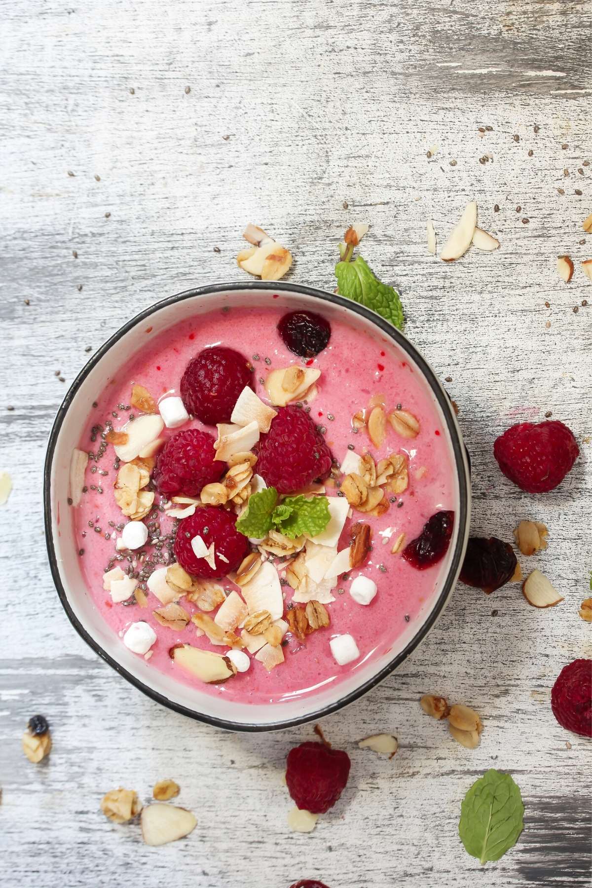 smoothie bowl topped with fresh raspberries, granola, and coconut.
