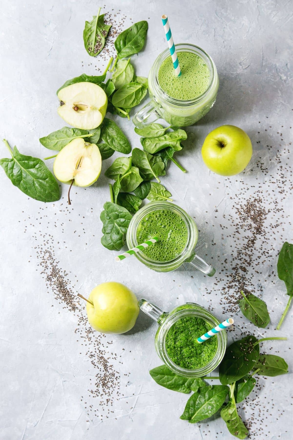 green smoothie on a table with apple and spinach.