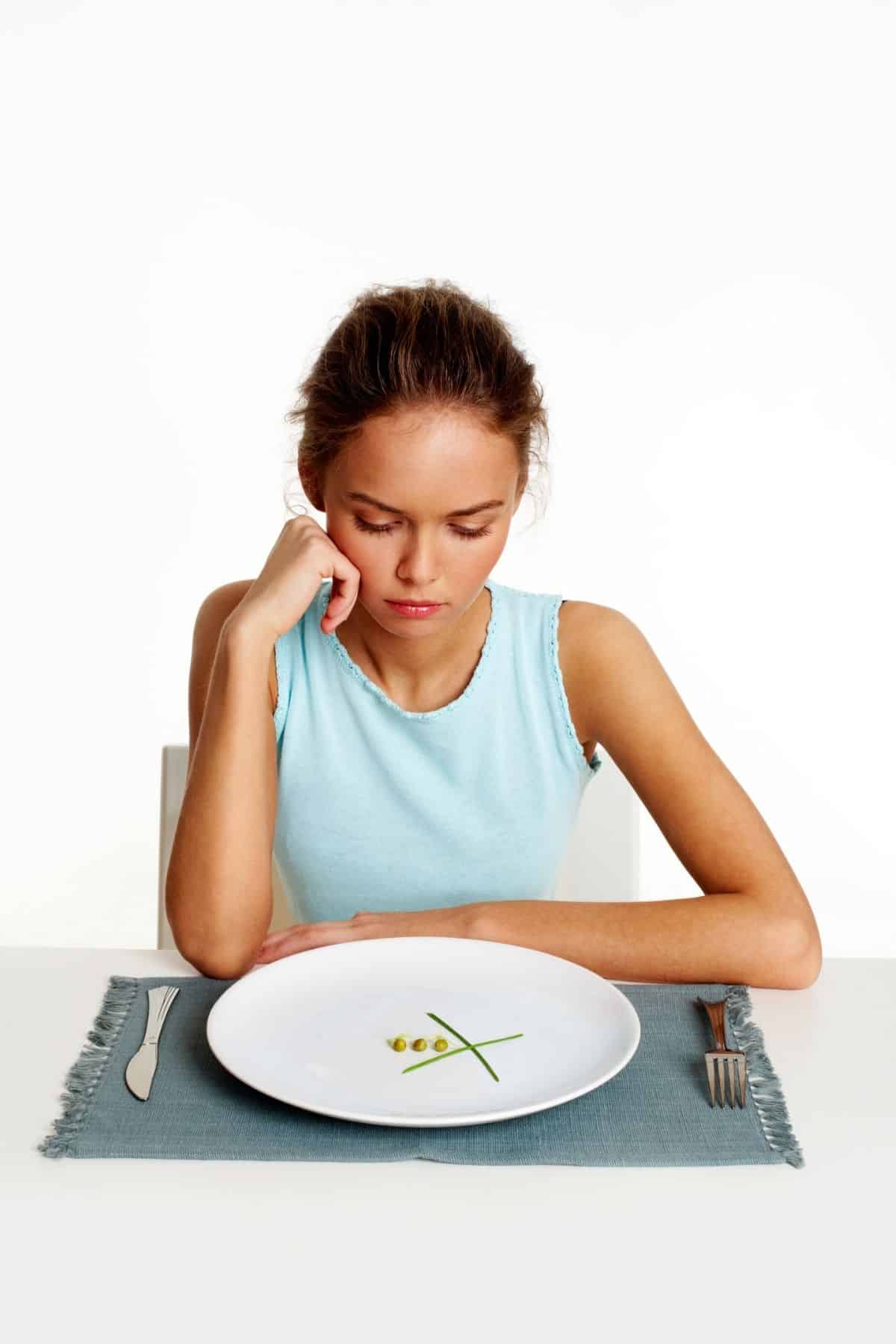 woman sitting in front of a plate with just a little bit of food on it