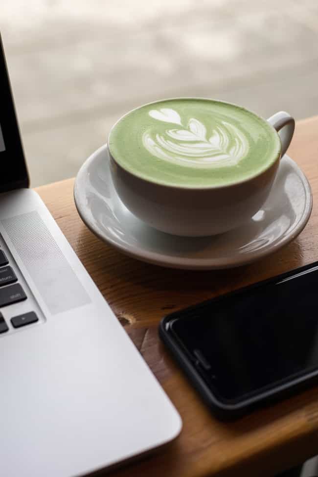 Matcha latte beside a computer.