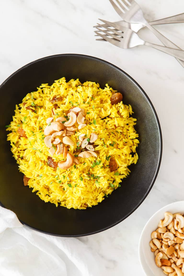 An Indian Rice Dish served with golden raisins and cashews. 
