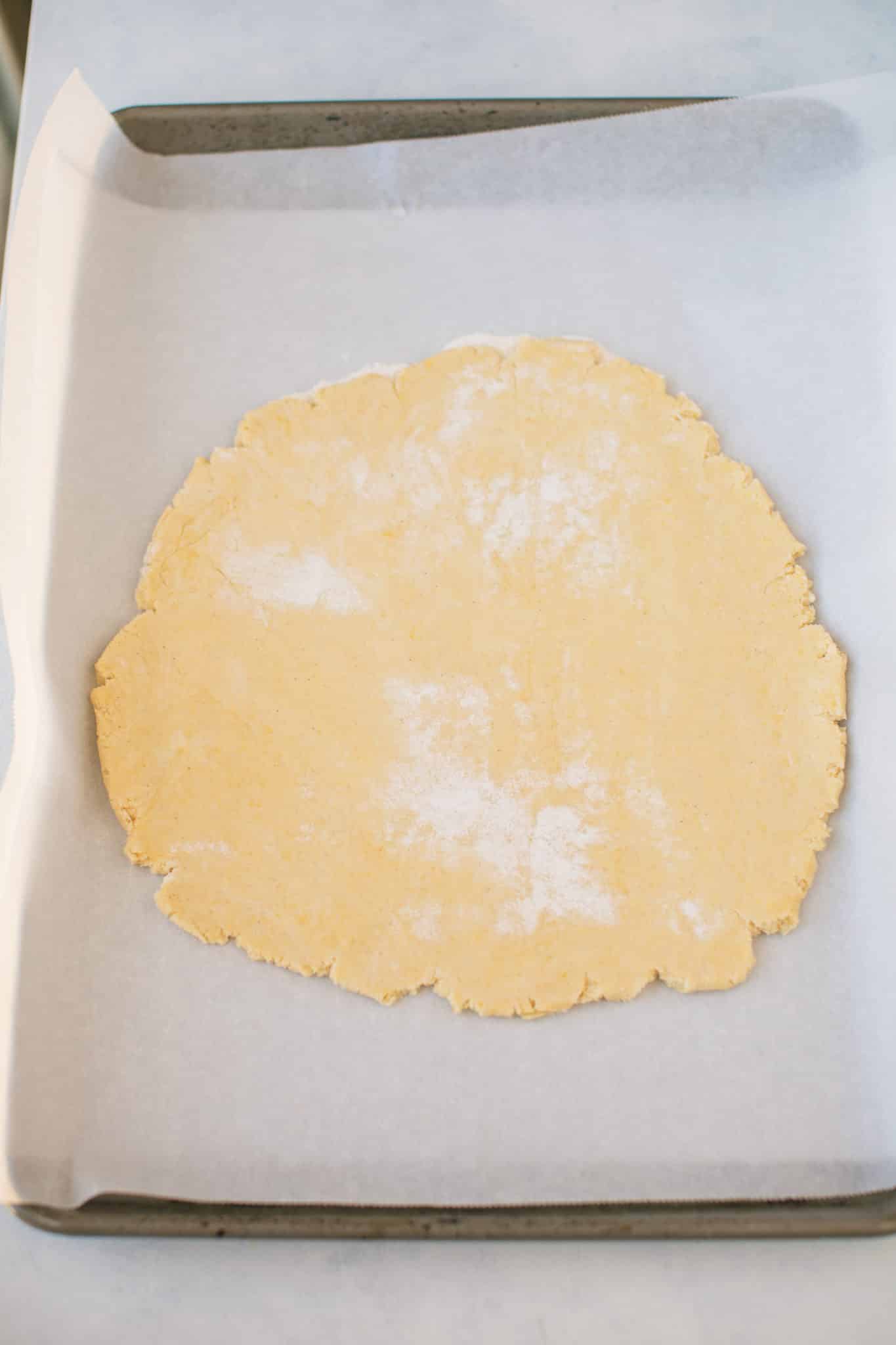 cassava pizza crust rolled out on a baking sheet.
