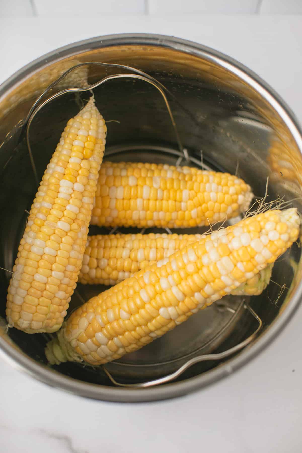 four pieces of corn on the cob inside an instant pot pressure cooker.
