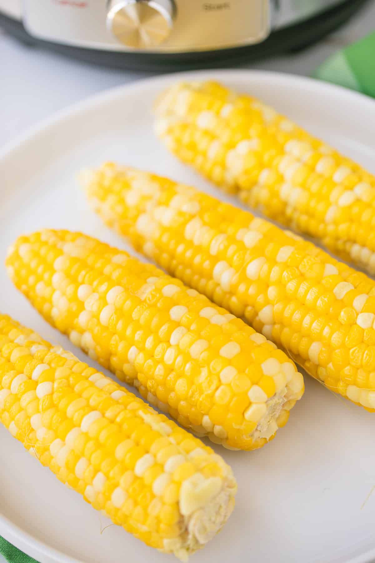 four pieces of cooked corn on a serving plate.