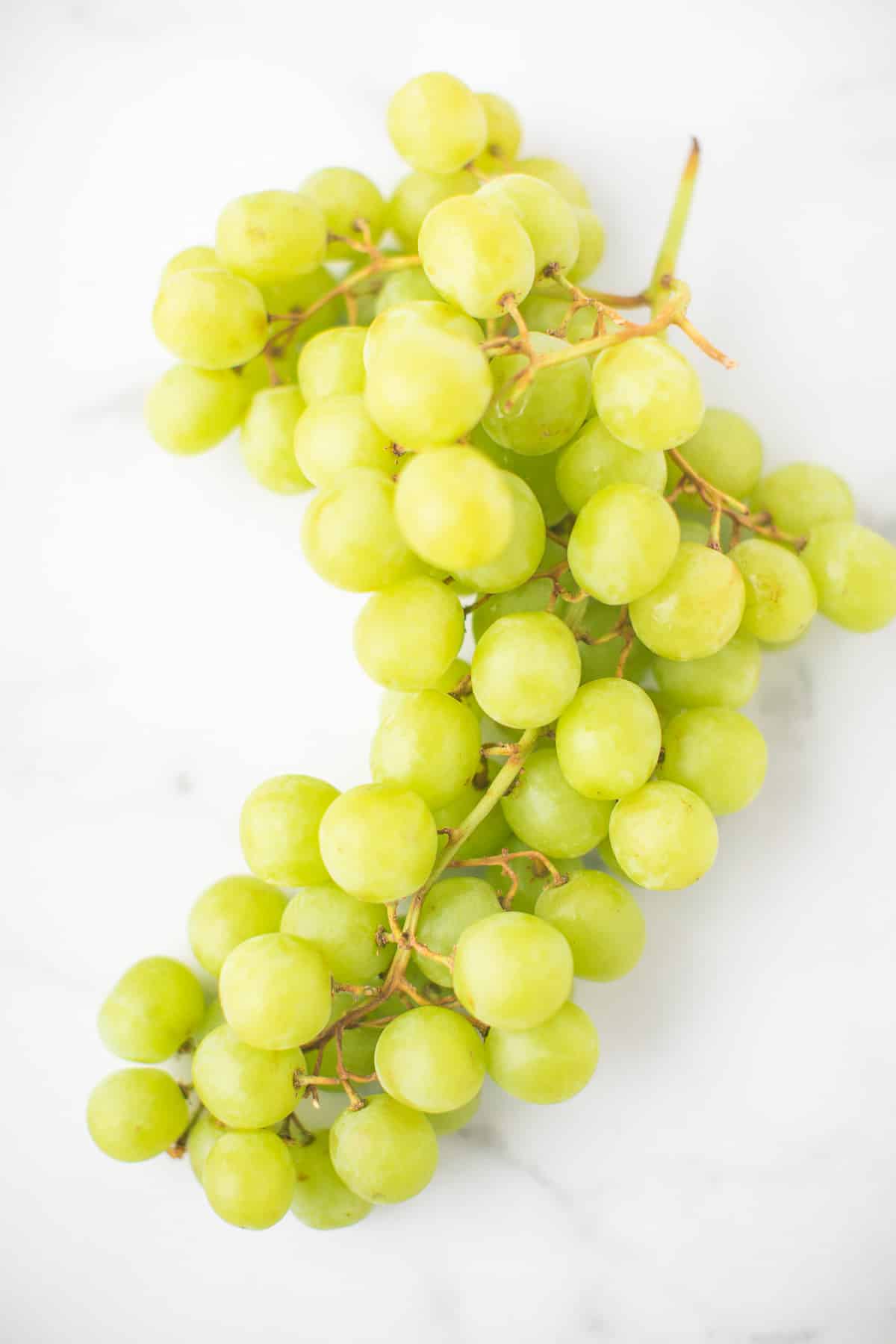 bunch of green grapes on a marble countertop.