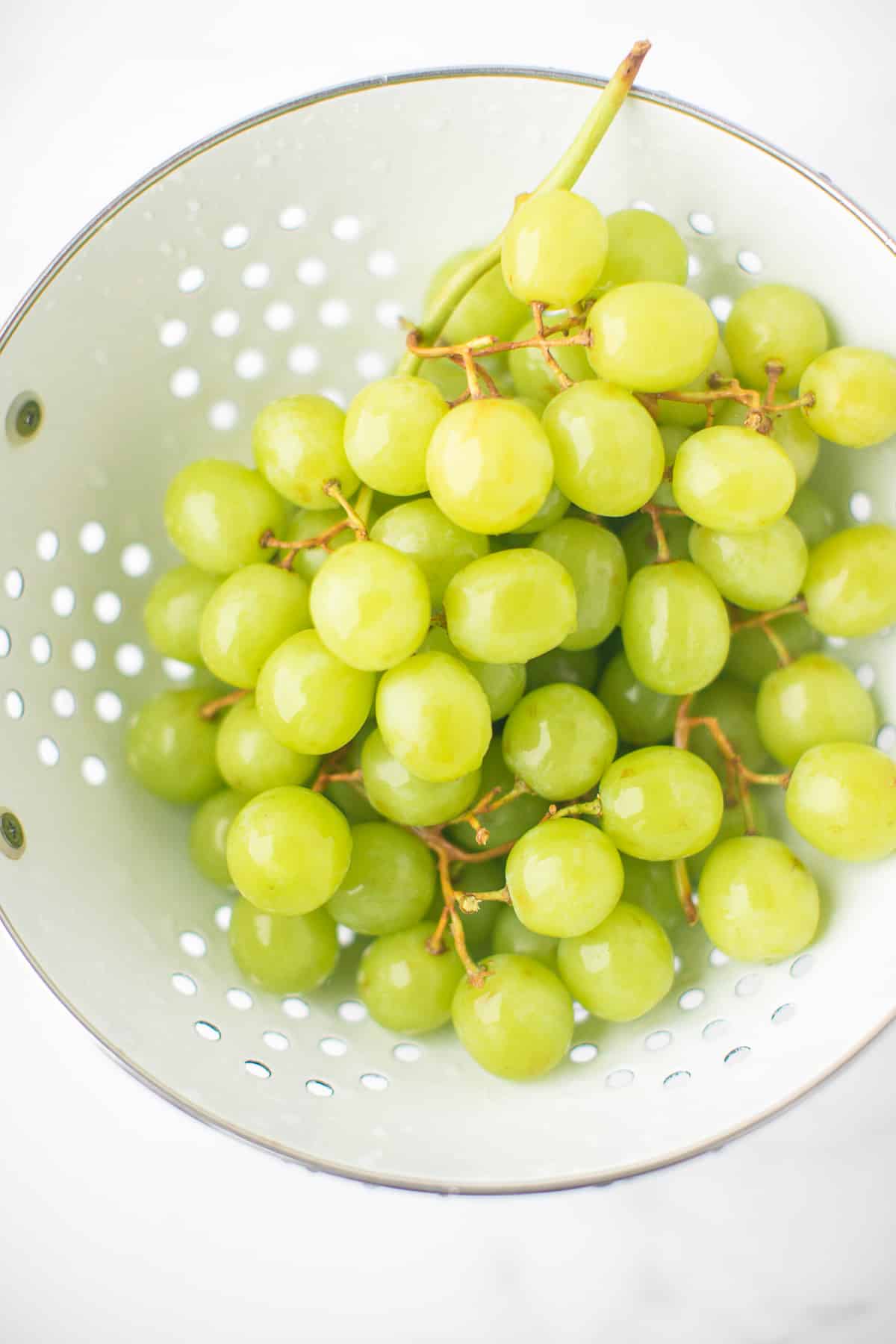 grapes being washed in a colander.