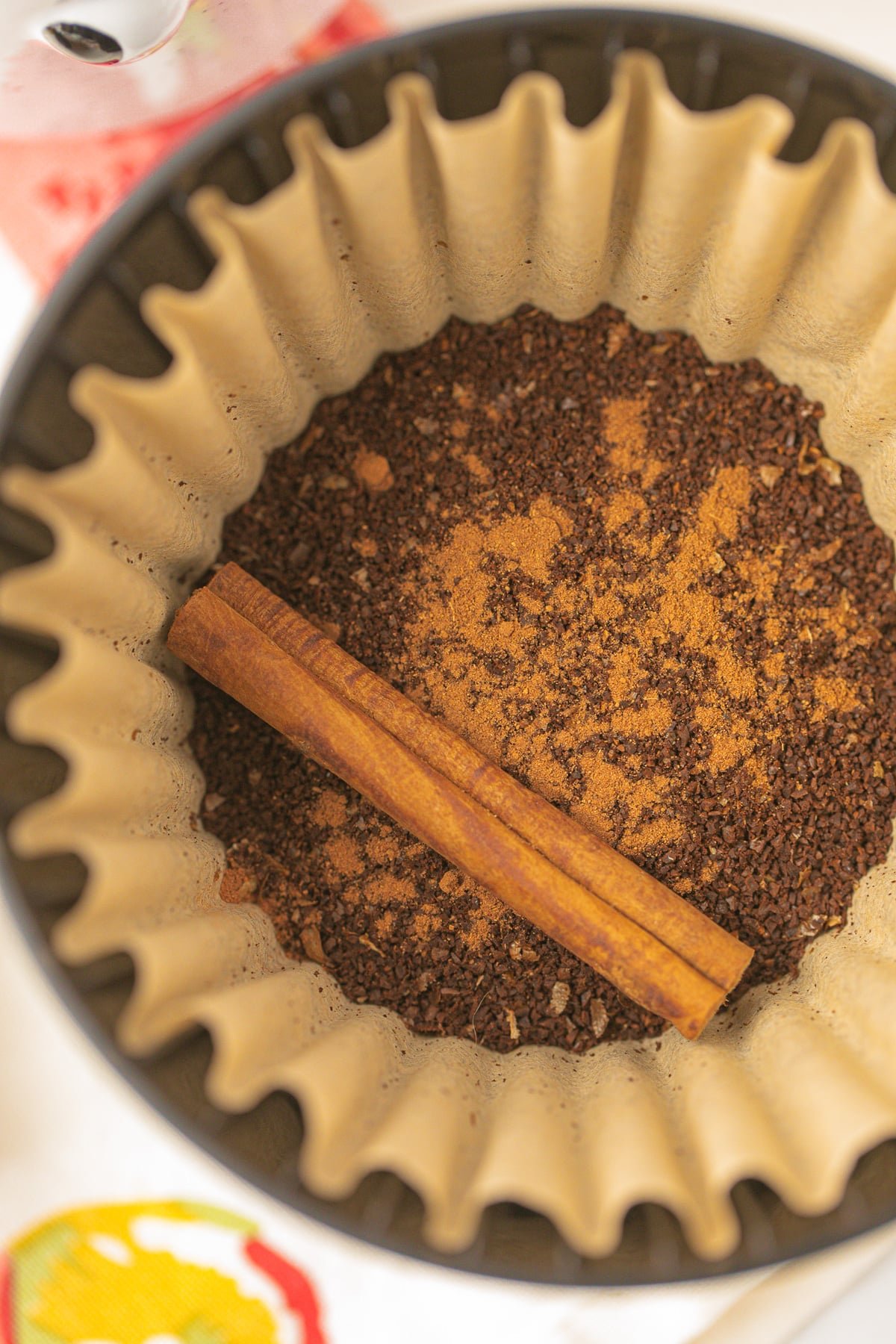 coffee filter with ground coffee, pumpkin spice, and a cinnamon stick.