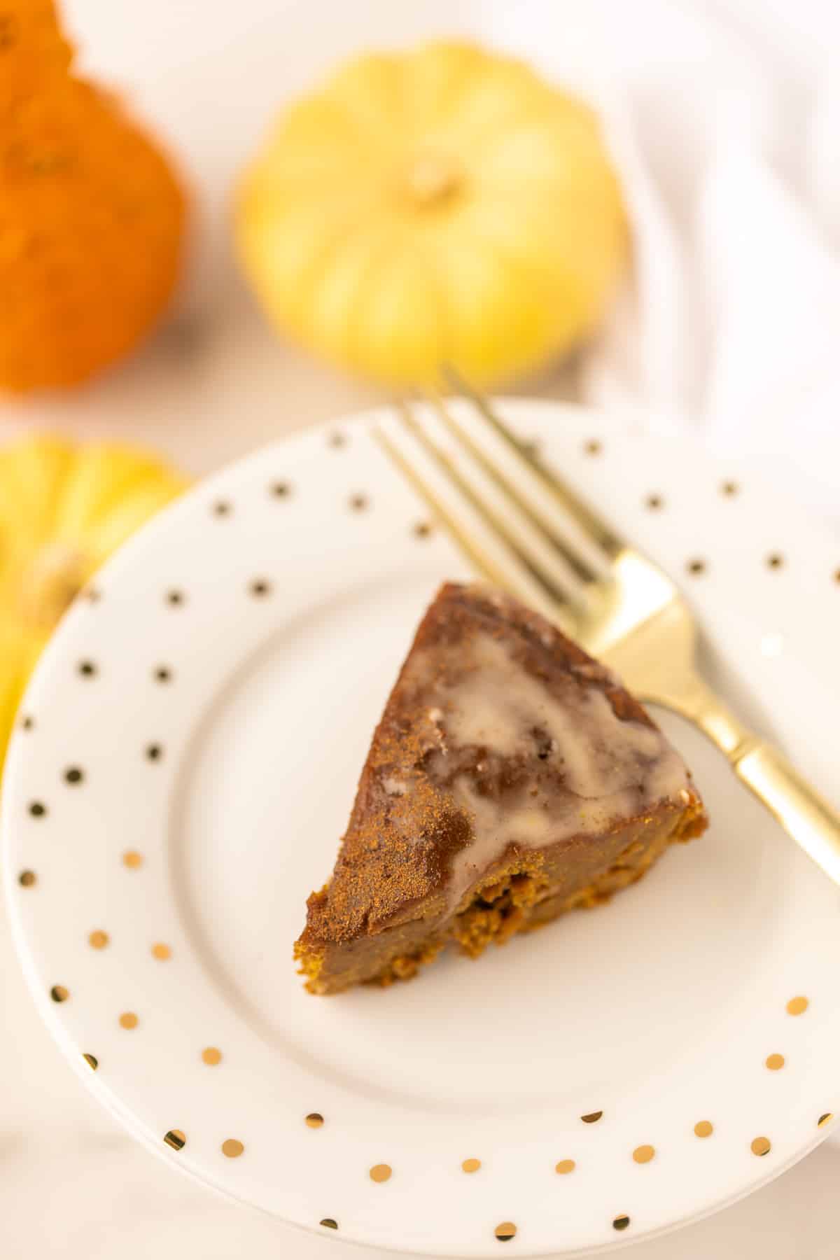 slice of baked instant pot pumpkin cake with drizzle on top and a gold fork.