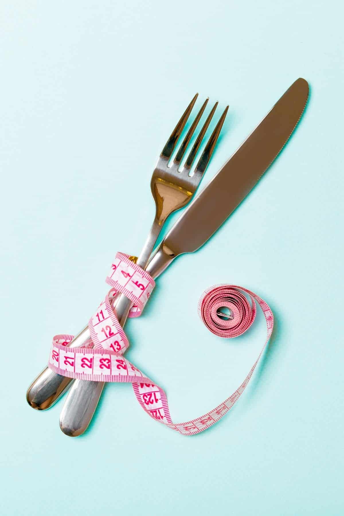 fork and knife wrapped up with a measuring tape