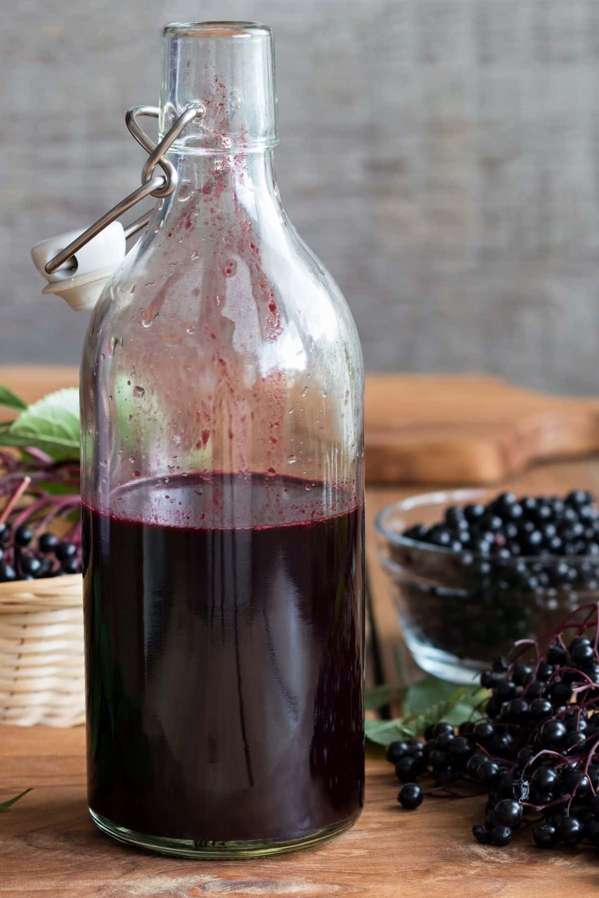 elderberry syrup in a jar on a table with elderberries.