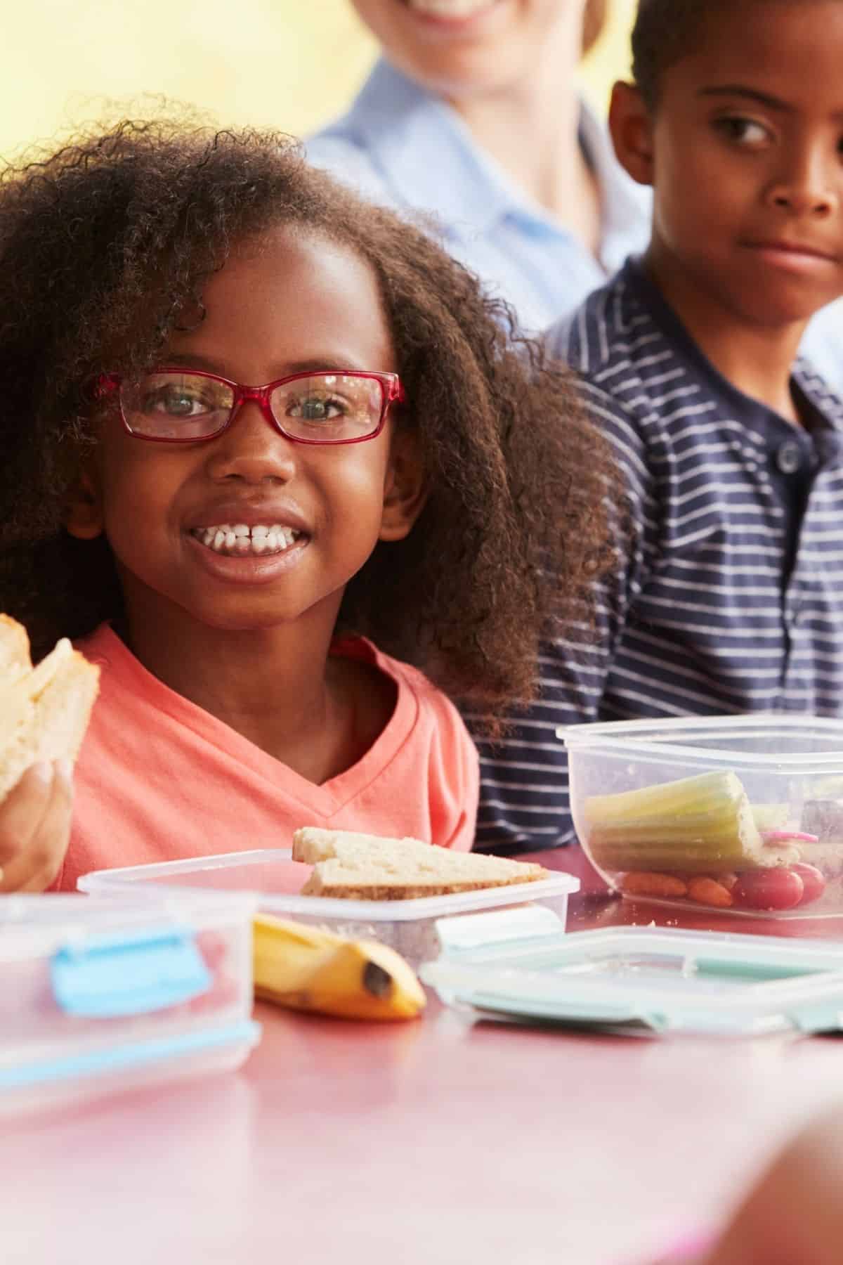 young child in glasses eating lunch.