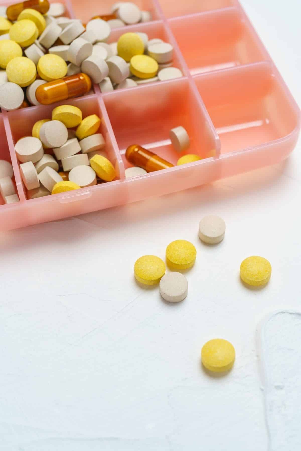 pink pill holder with tablets and capsules.