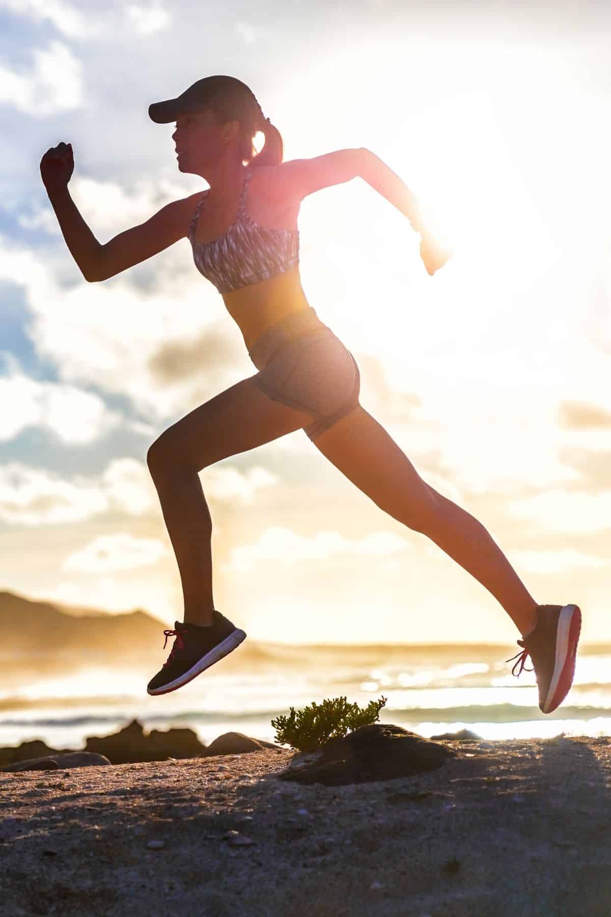 female athlete sprinting on a beach.