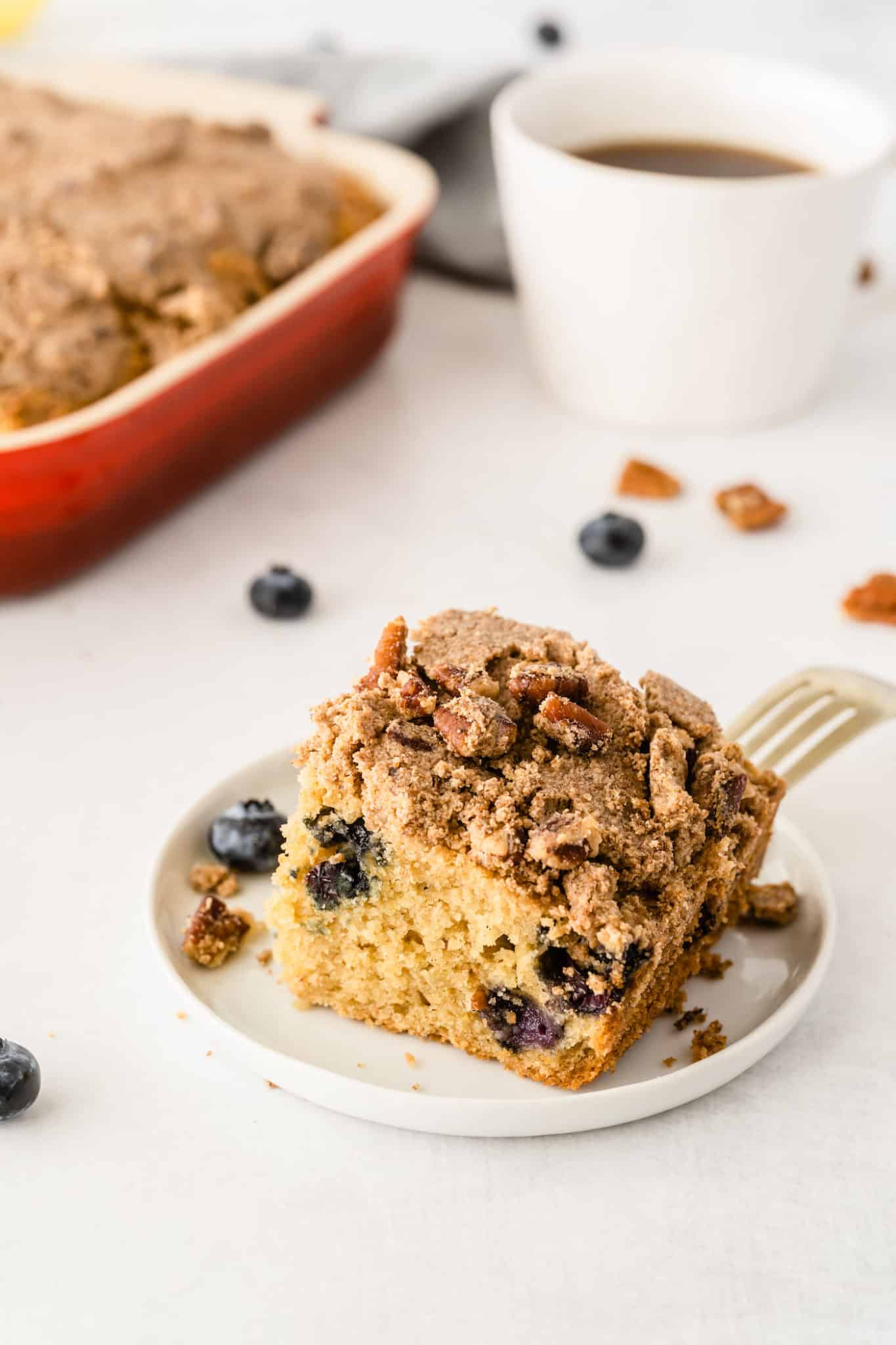 slice of gluten-free blueberry coffee cake served with with a cup of coffee.
