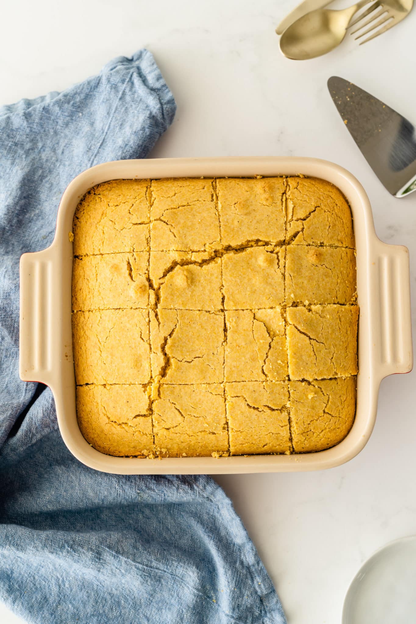 cornbread cooked in a square baking dish cooling on a countertop.