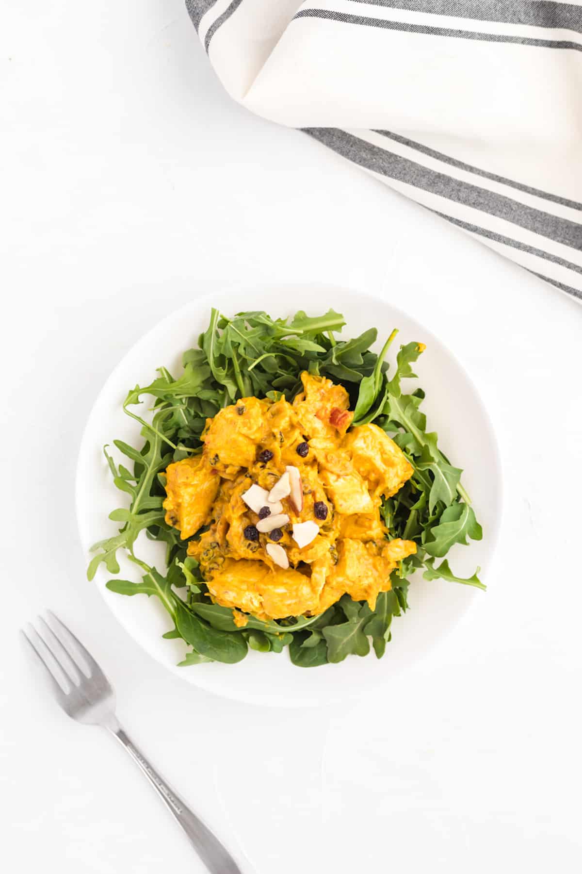 A plate of curry chicken salad on arugula