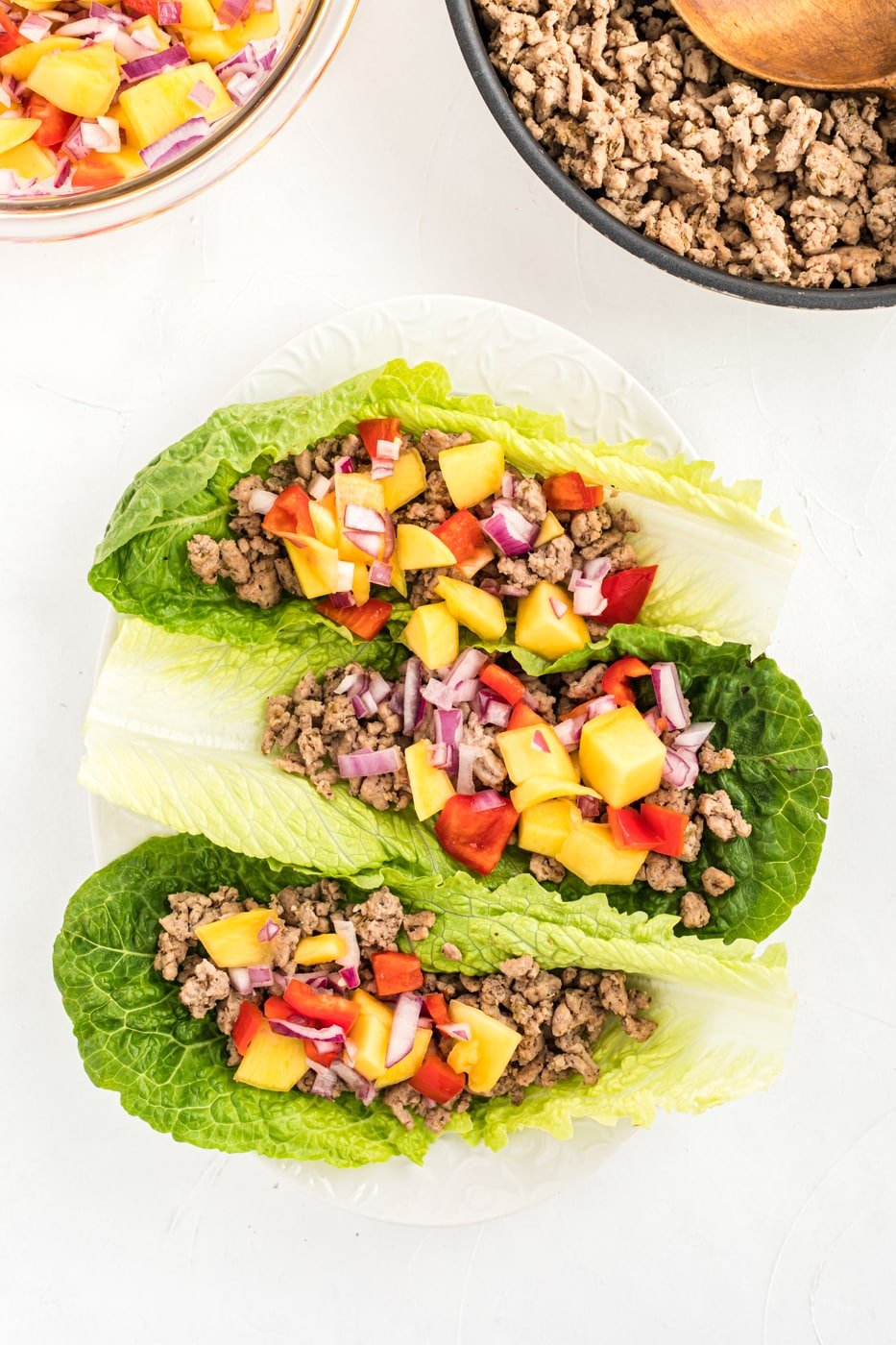 ground chicken lettuce tacos on a plate with mango salsa.