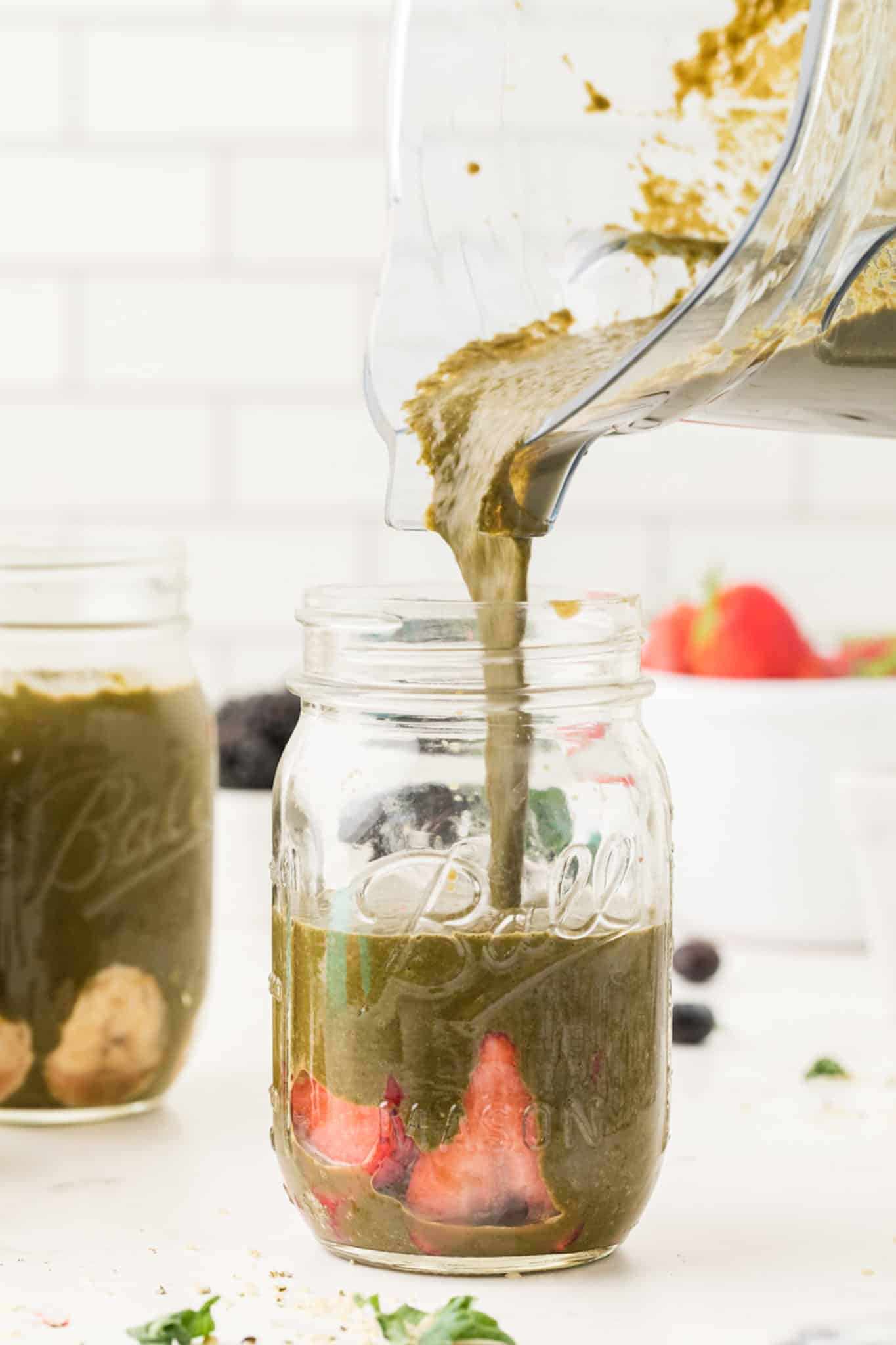 photo showing pouring a green smoothie into a jar.