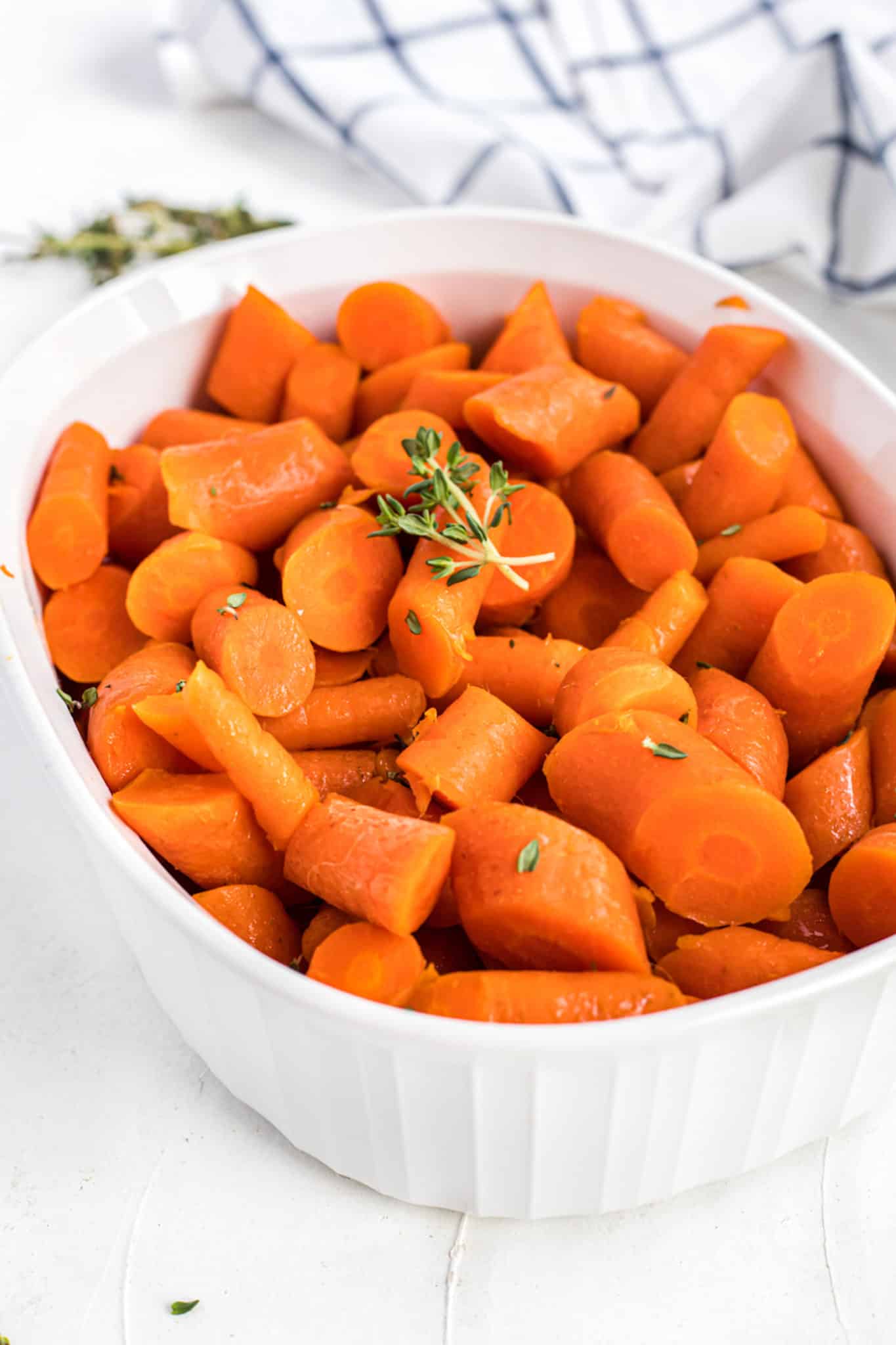 Instant pot cooked carrots in white casserole dish with thyme.