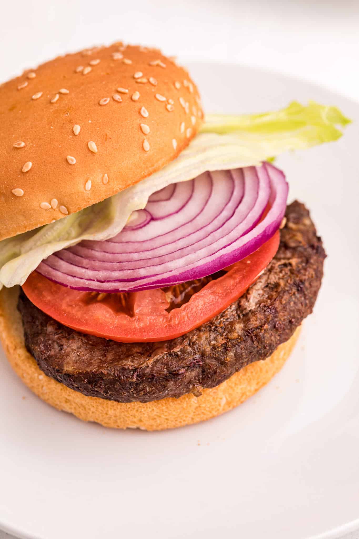 A air fryer frozen hamburger with onion and tomato.