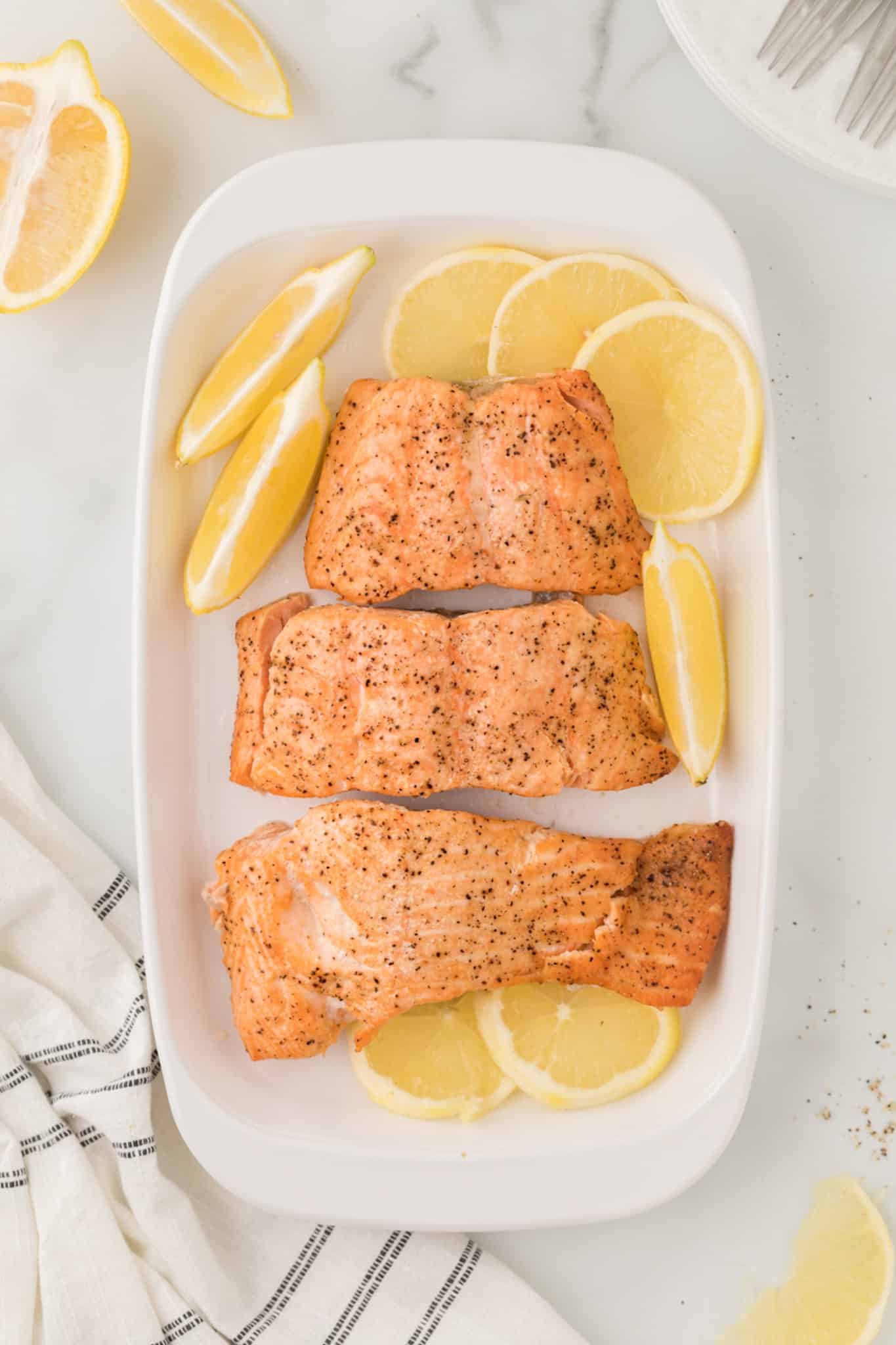 cooked salmon fillets on a serving dish with lemon slices.