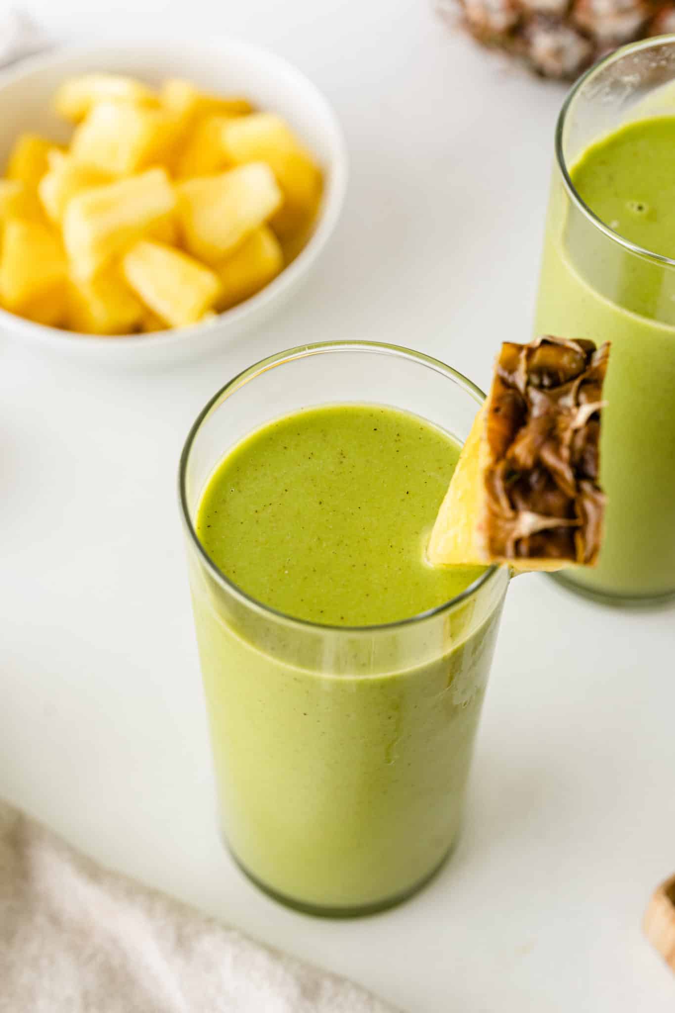 green smoothie served in a glass with a wedge of fresh pineapple