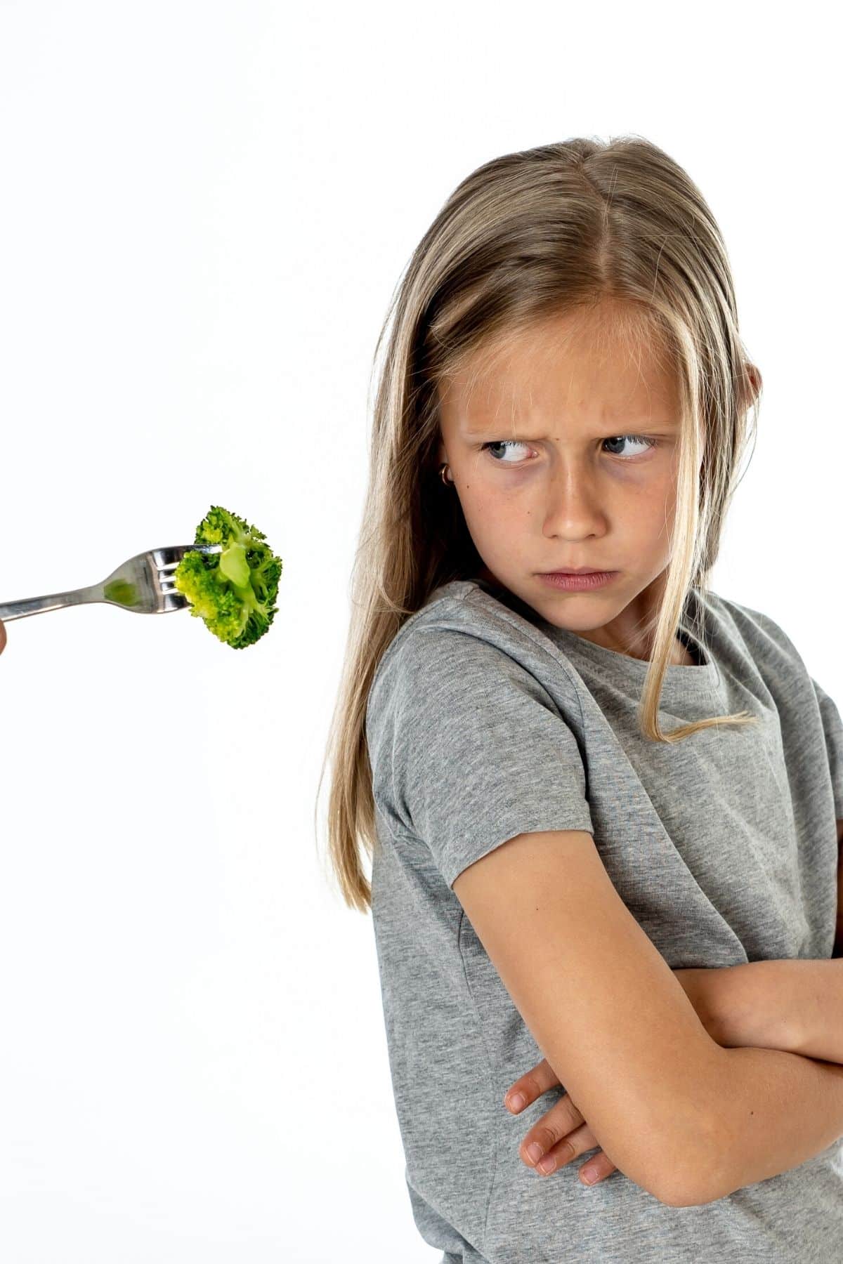 young girl refusing a bite of broccoli.