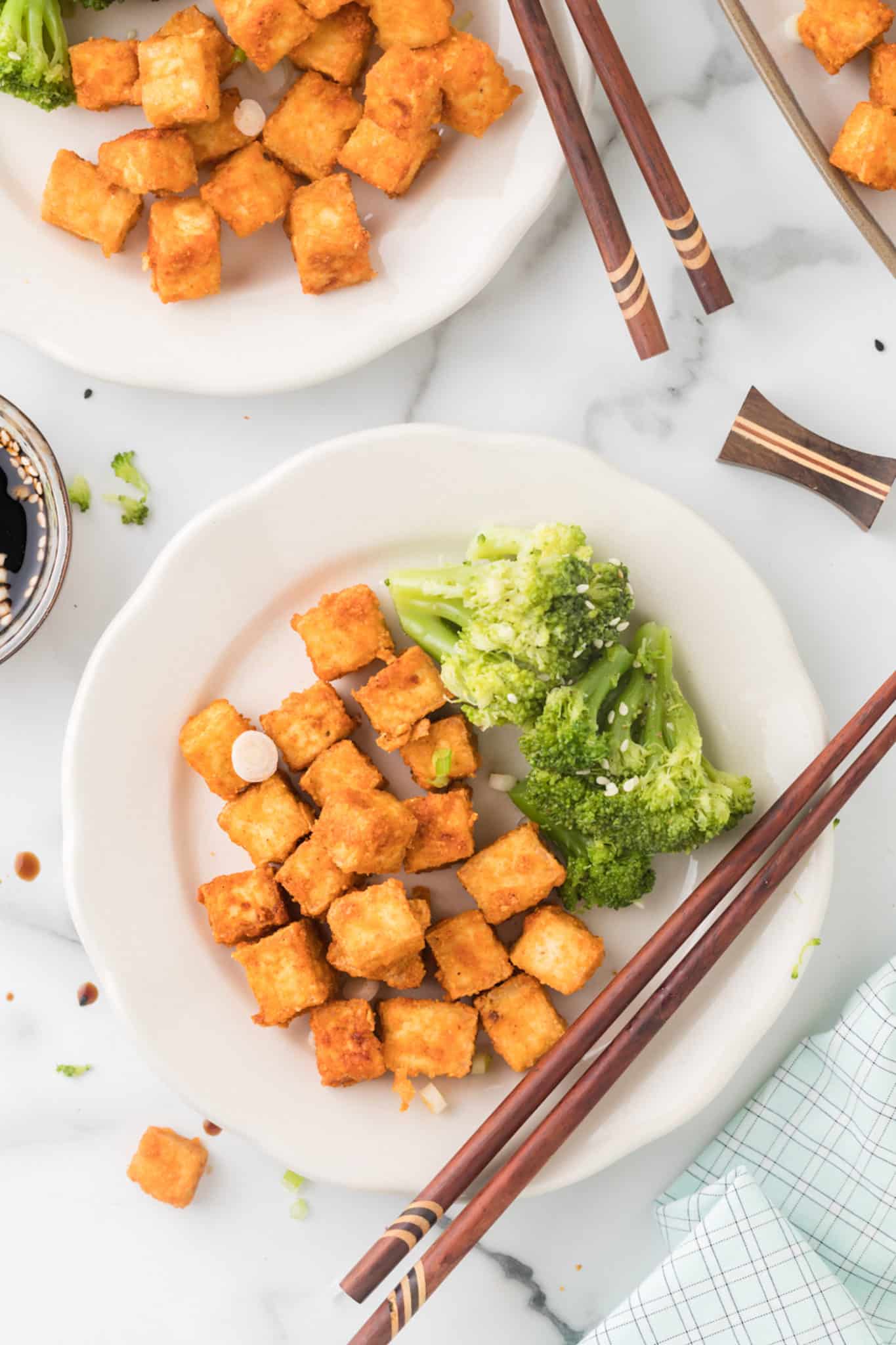 two plates of tofu served with broccoli
