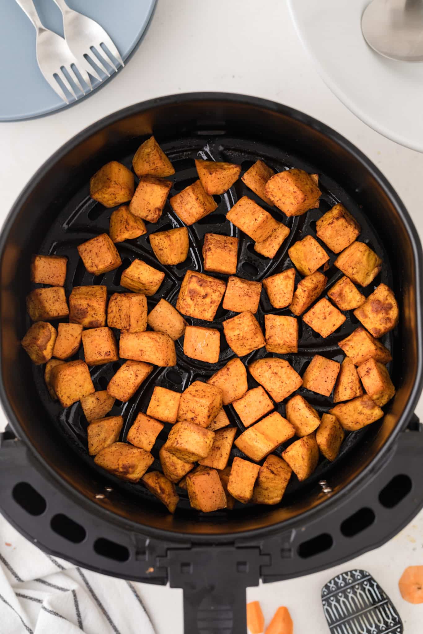 sweet potato cubes in an air fryer basket.