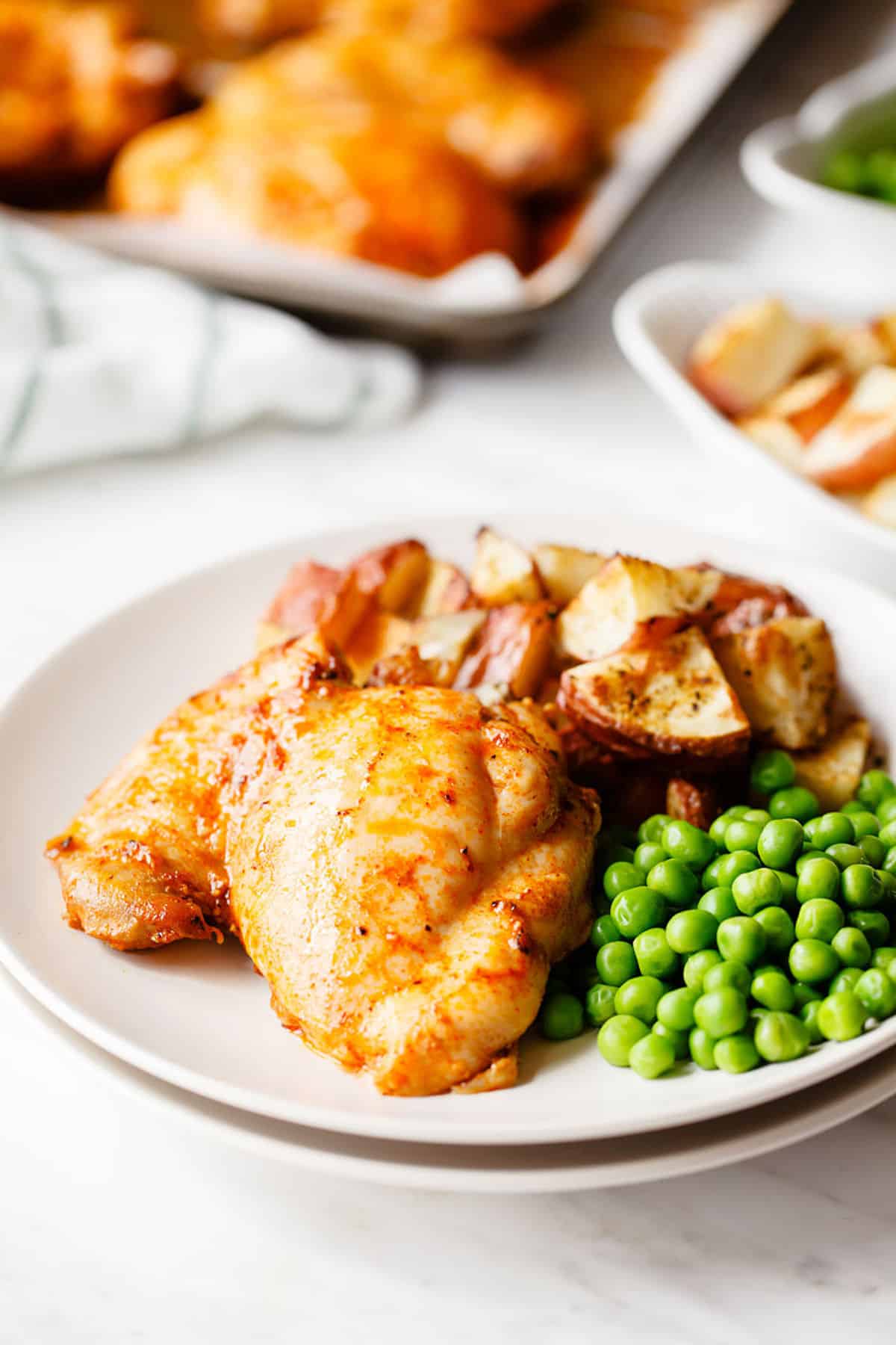 paprika chicken on a plate with peas and potatoes.