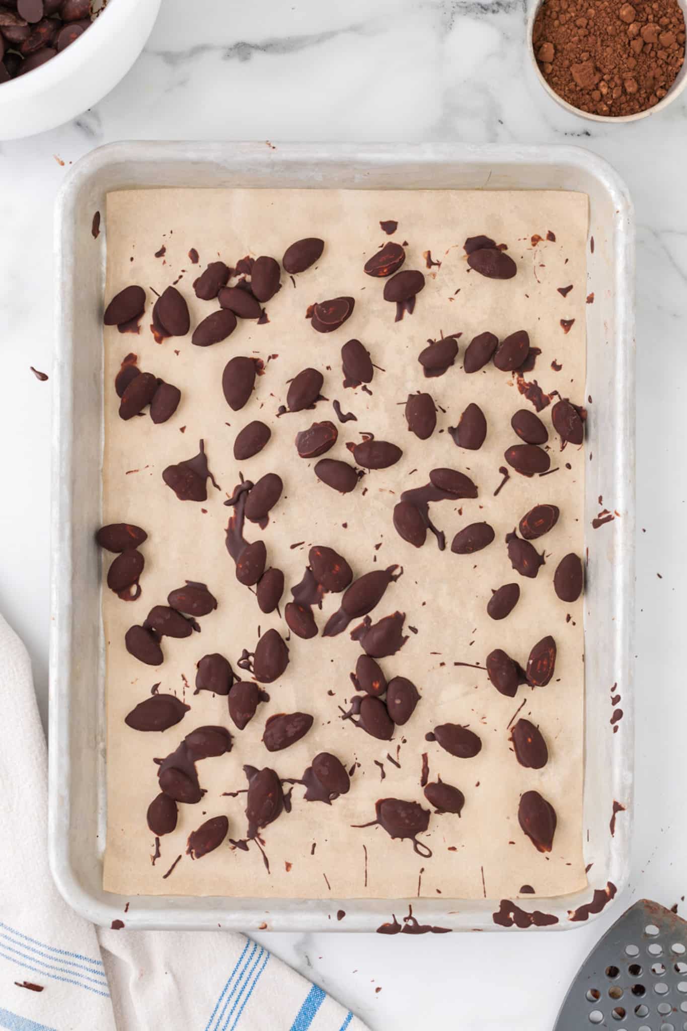 chocolate covered almonds on a sheet pan.