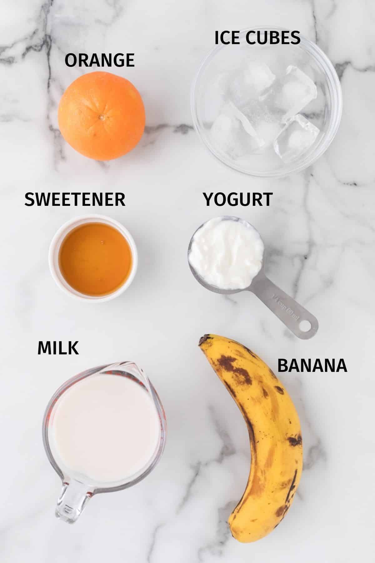 ingredients for orange banana smoothie on table with labels.
