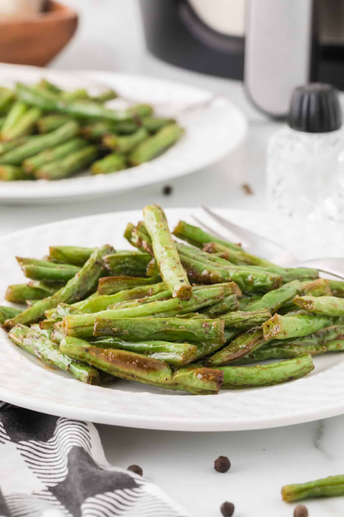 two plates of cooked air fryer green beans.