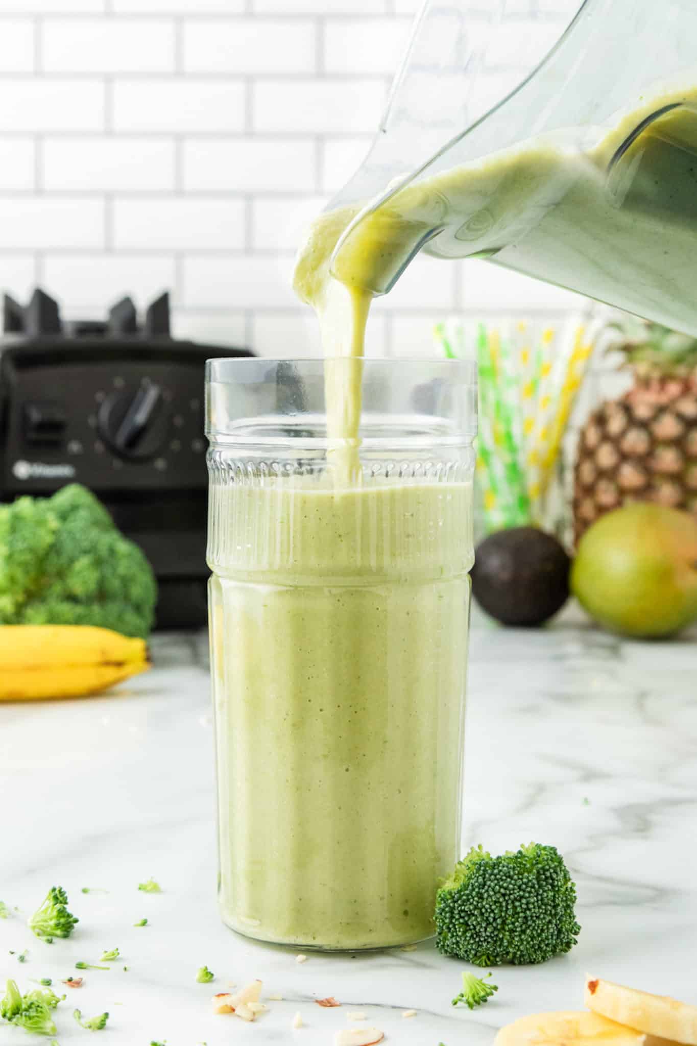 pouring broccoli smoothie into a glass.