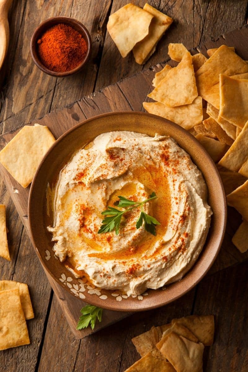 Bowl of hummus with crackers next to it.