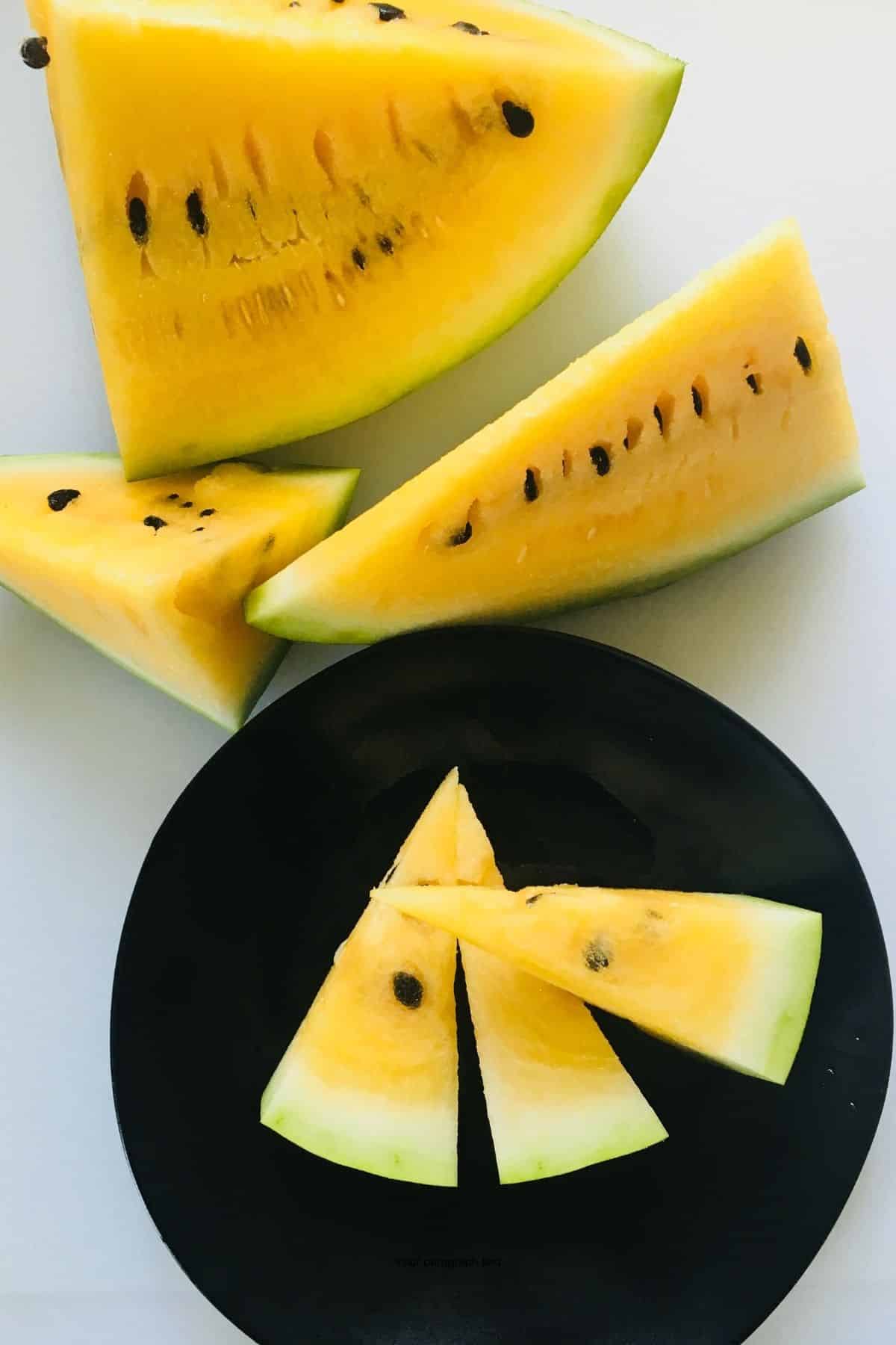 Yellow watermelon cut into pieces on a plate. 