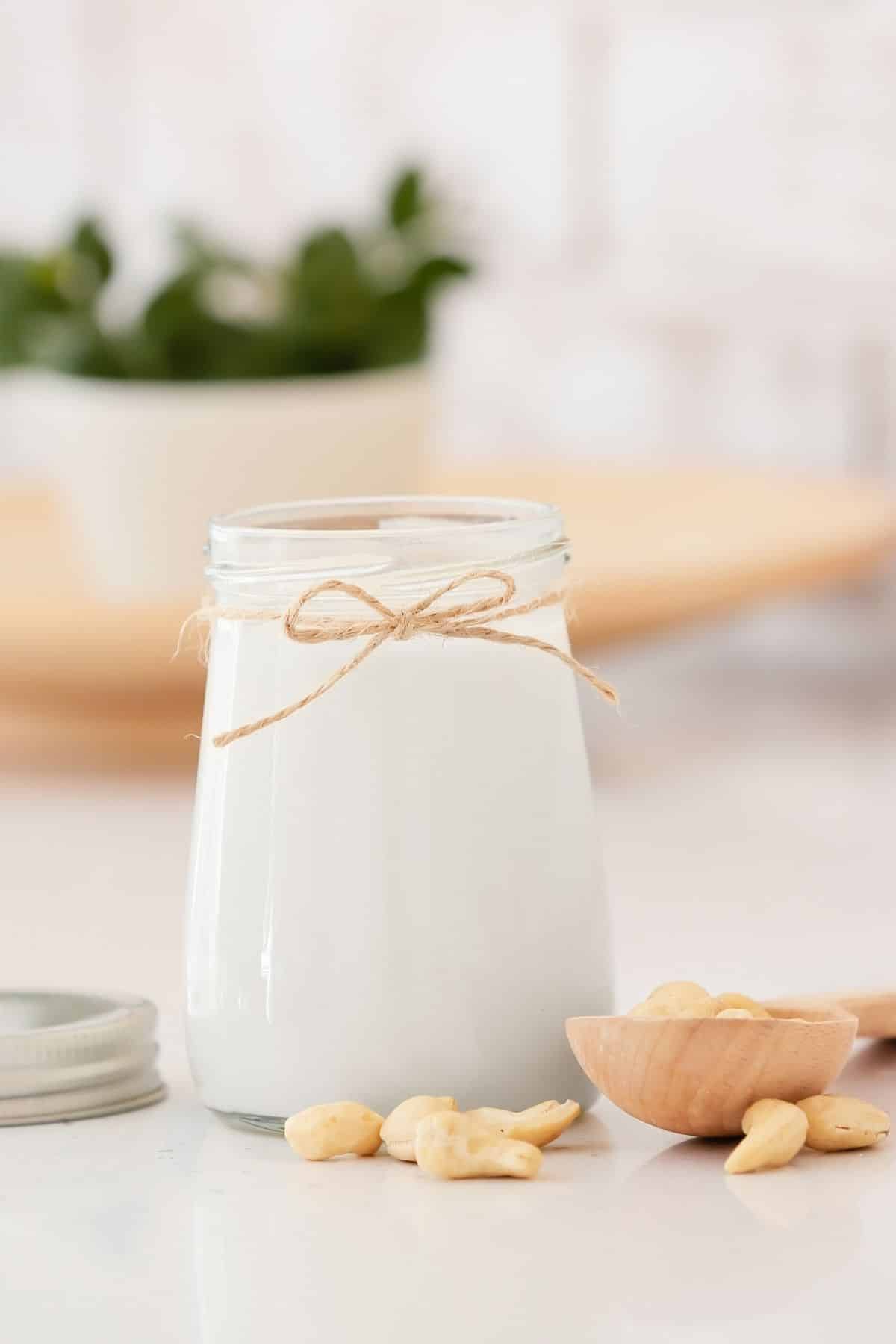 glass of cashew milk with a string tied around the neck of the jar.