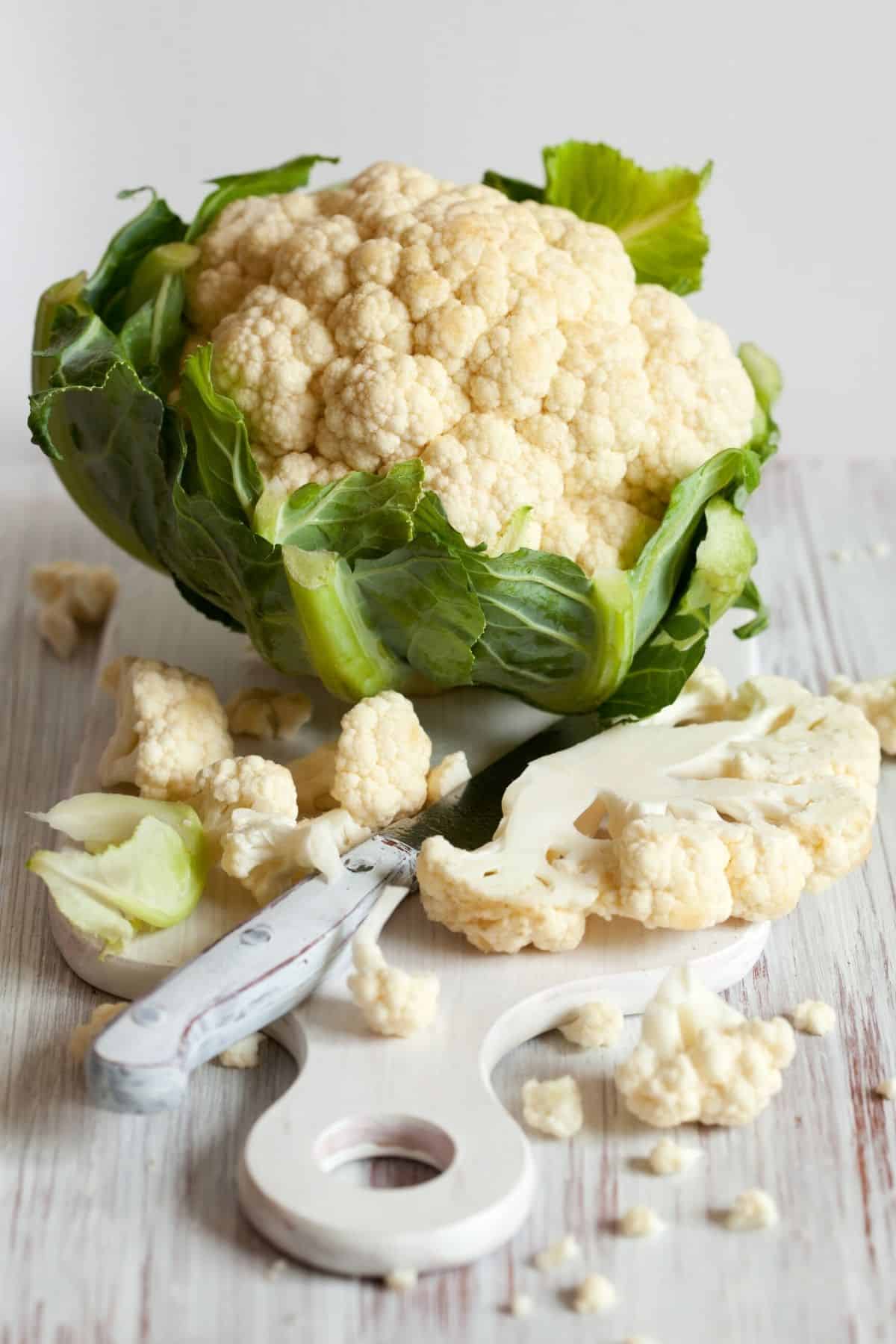 head of cauliflower on a table with a knife to cut into florets.
