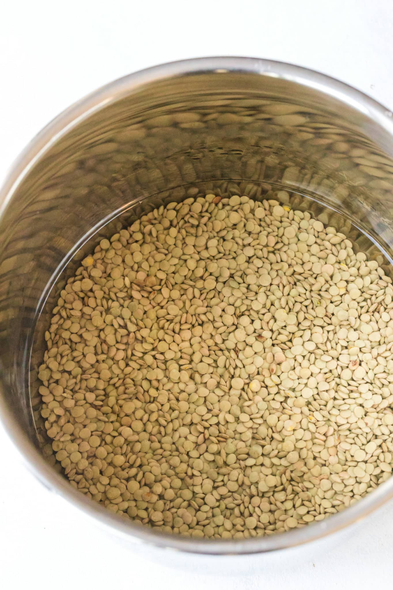 green lentils with water inside instant pot ready to cook.