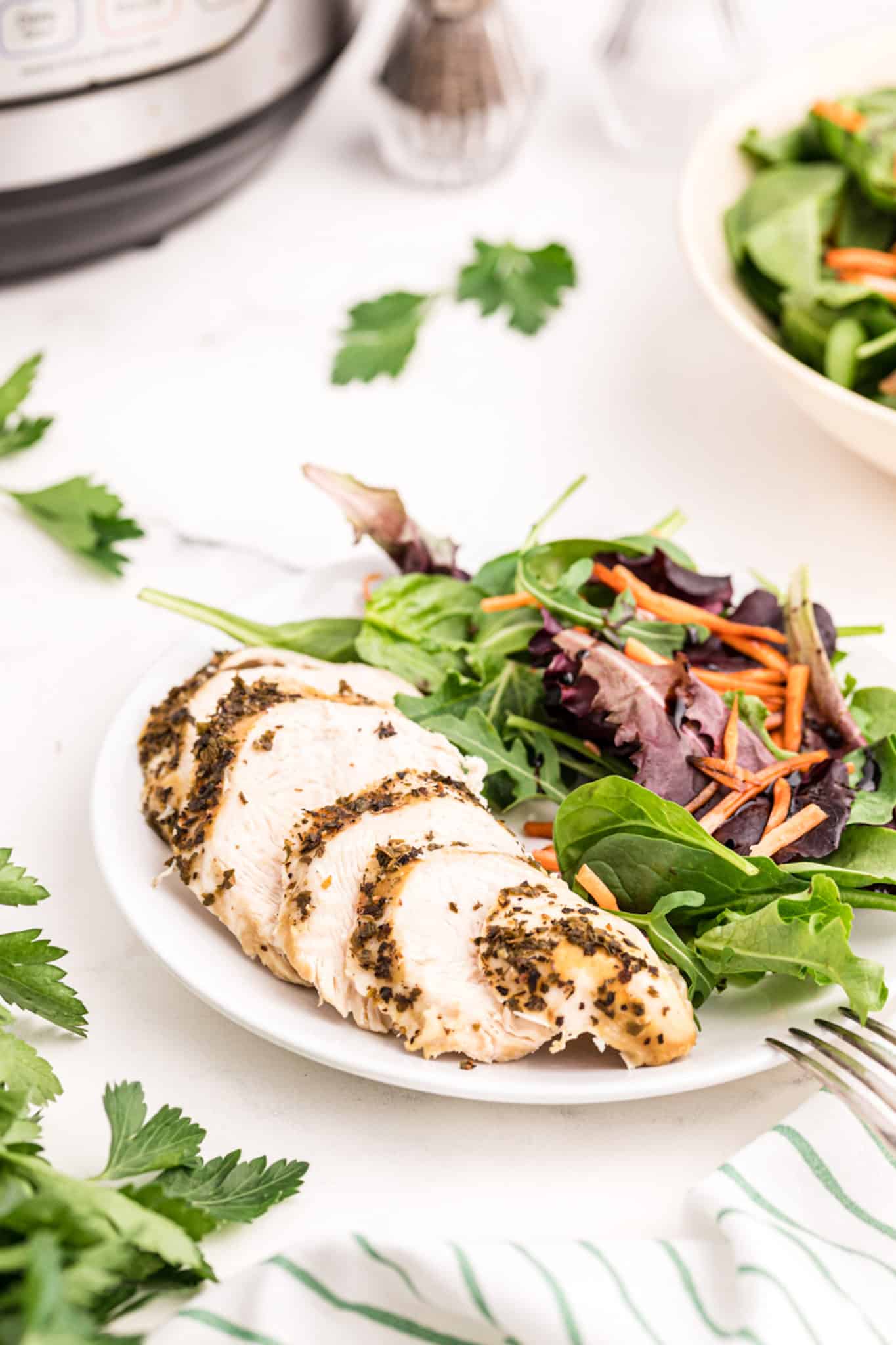 Sliced instant pot turkey tenderloin on a plate with green salad.