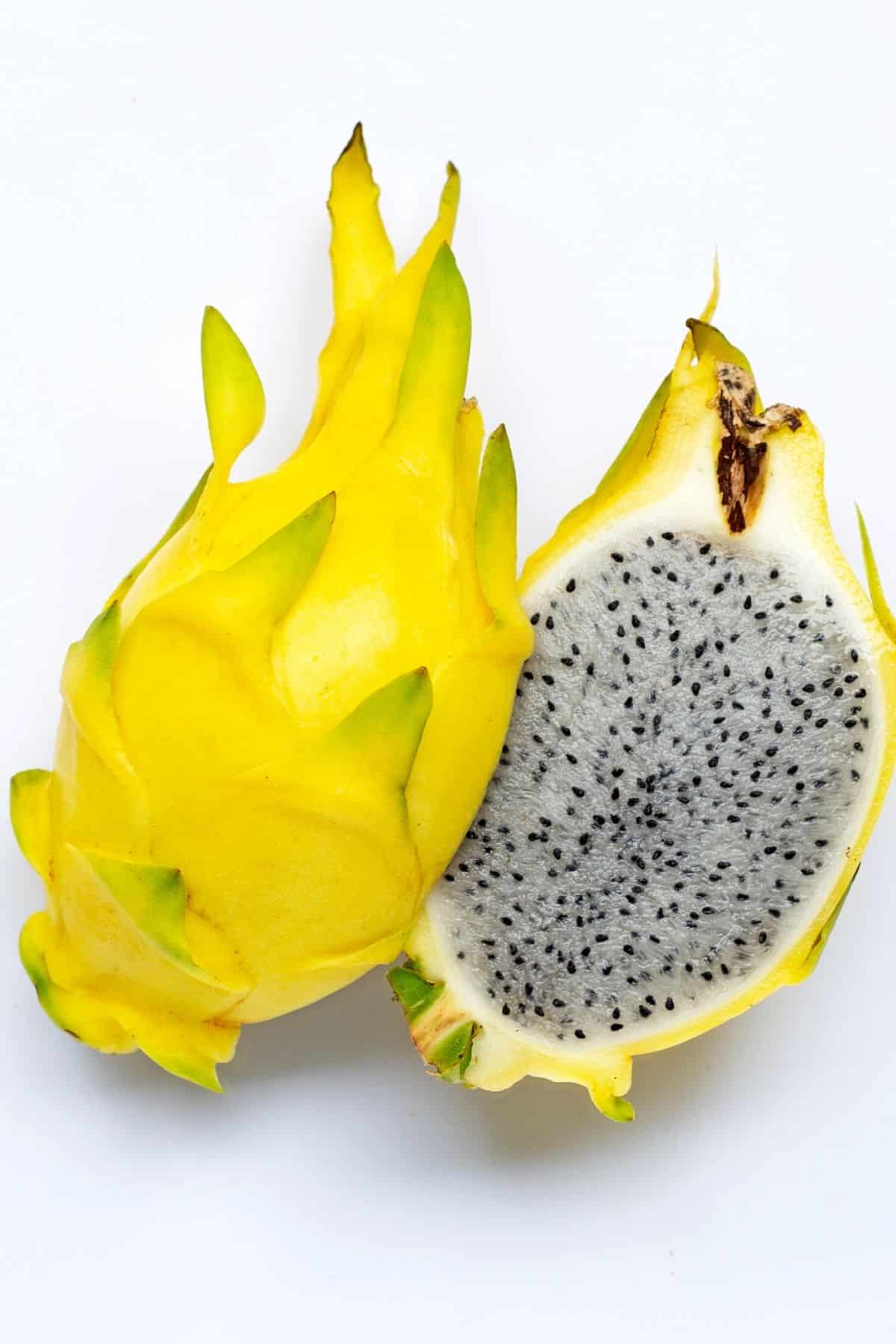 A large yellow dragonfruit cut in half on a white surface.