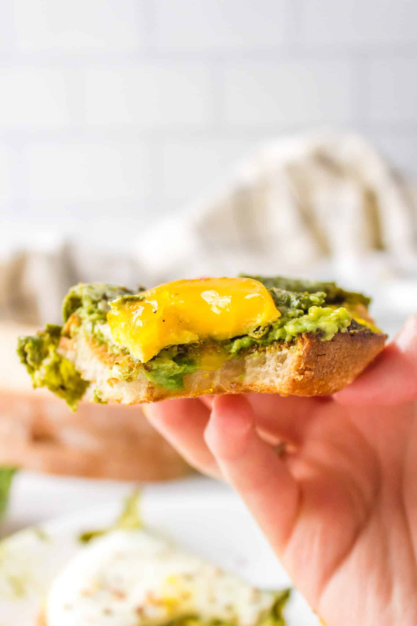 Side view of a bite taken from pesto eggs on avocado toast.