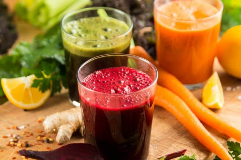 three colorful juice cleanse recipes on table.
