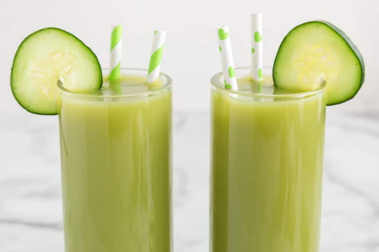 Two glasses of cucumber celery juice with cucumber wheels and straws.