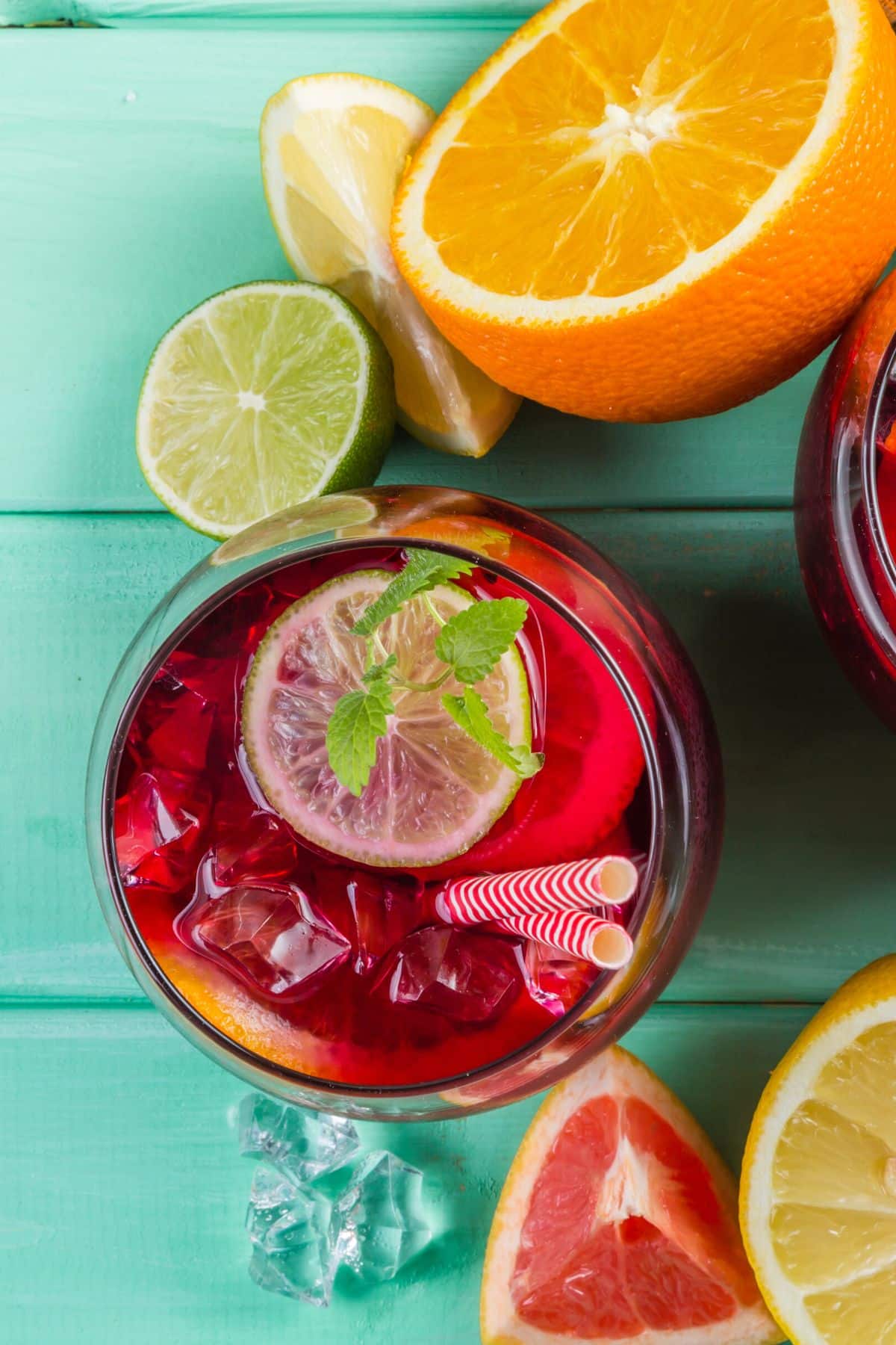 Glass filled with virgin sangria mocktail with two striped straws.
