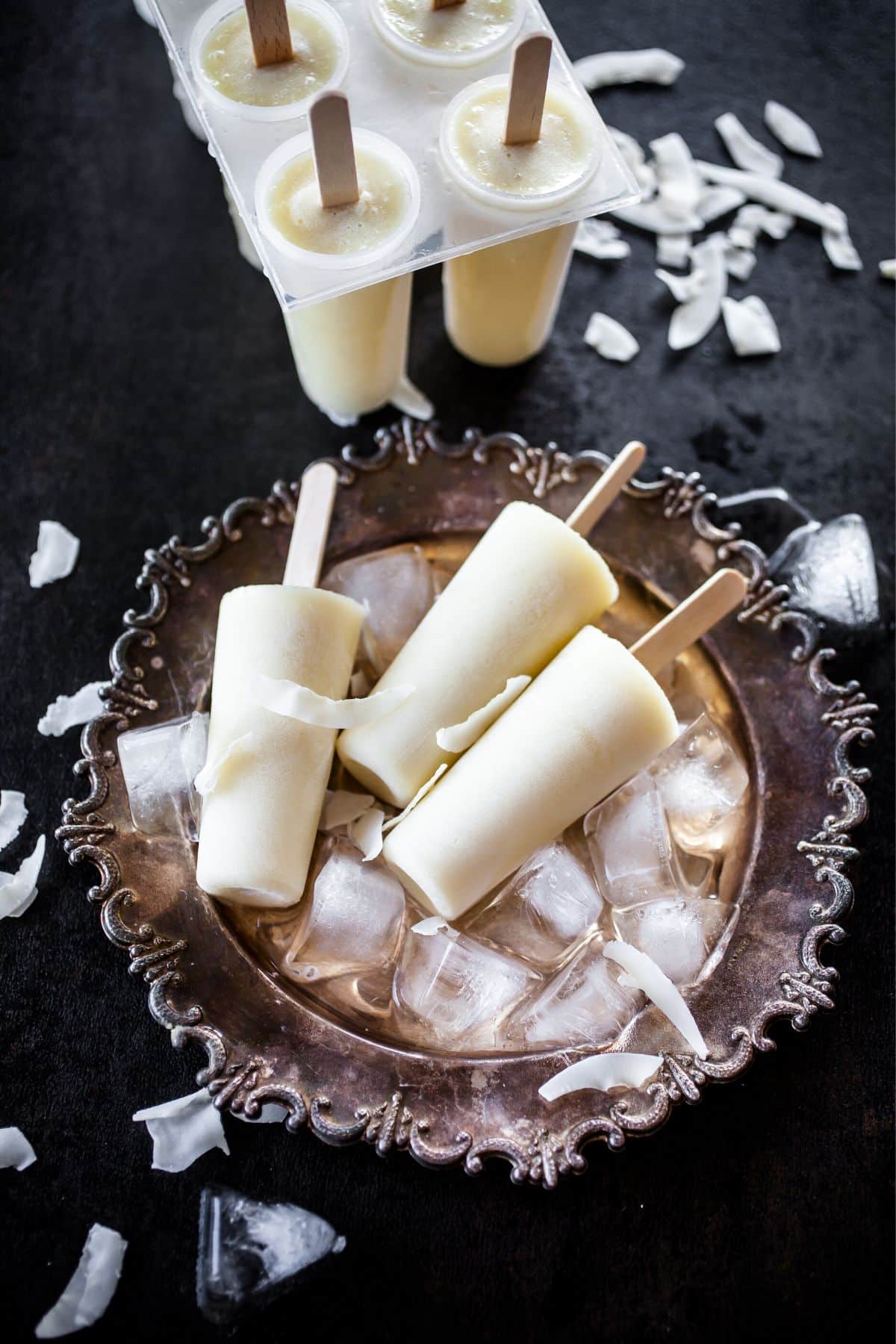 Banana popsicles on a decorate plate with ice.