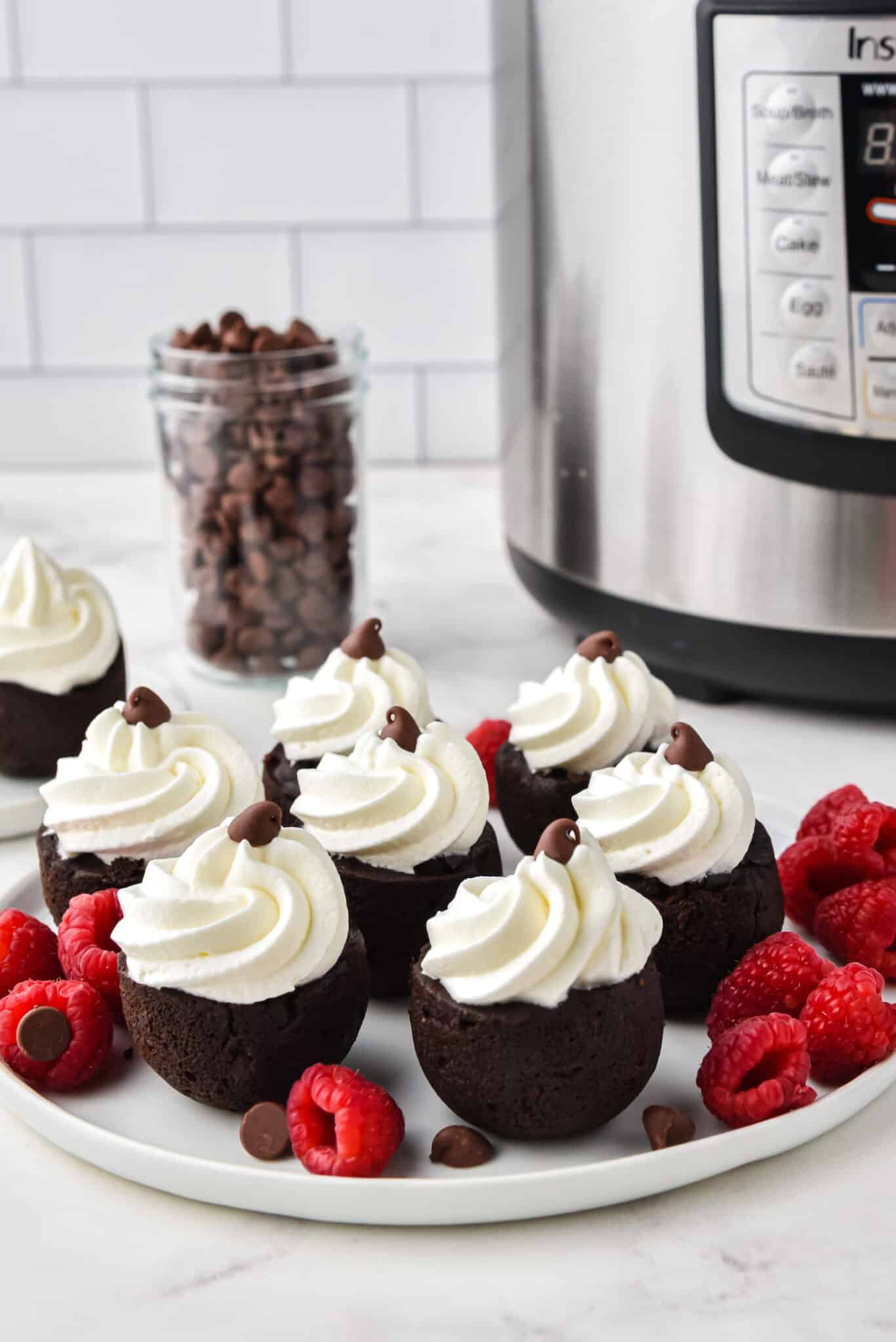 Instant Pot brownie bites topping with whipped cream on a white plate.