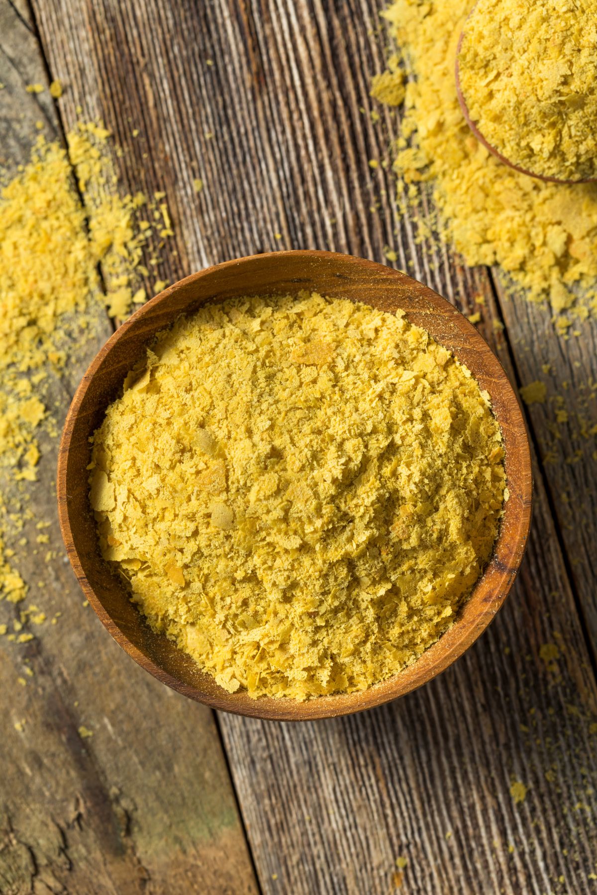 Bowl of nutritional yeast on wooden table.