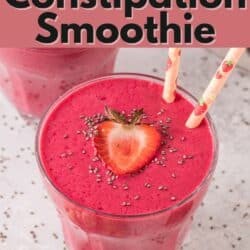 Two pink straws in a glass of strawberry smoothie topped with strawberries and chia.